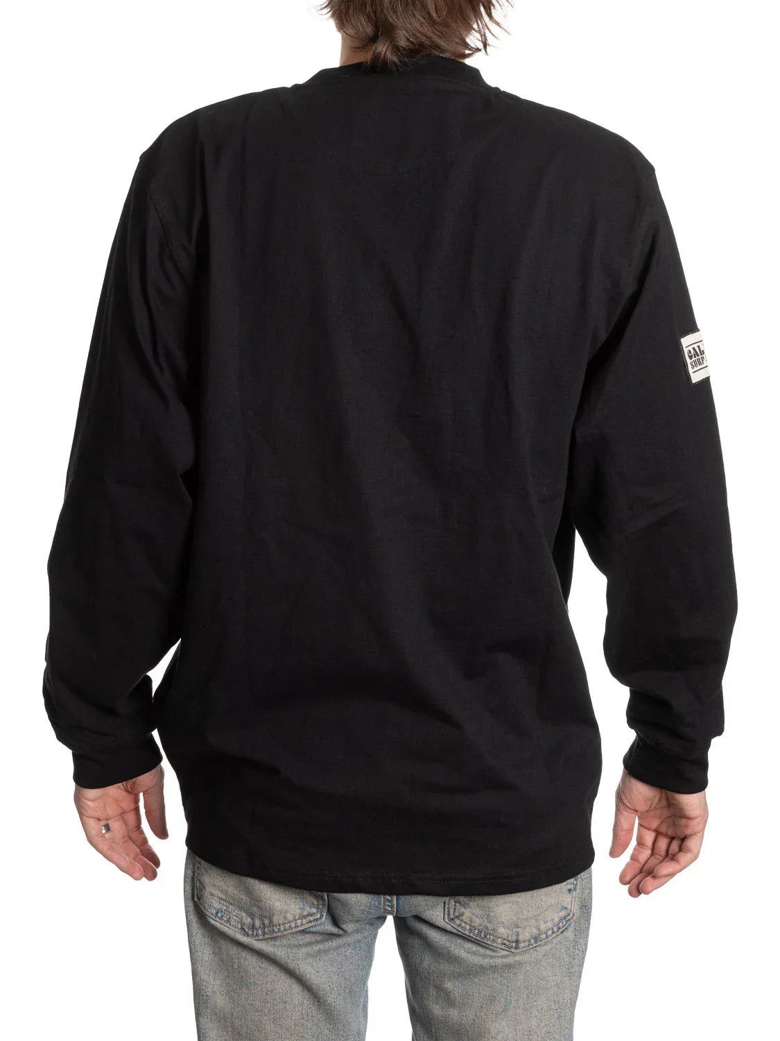 Back view of man in black long sleeve Chicago Henley shirt with patch, light jeans
