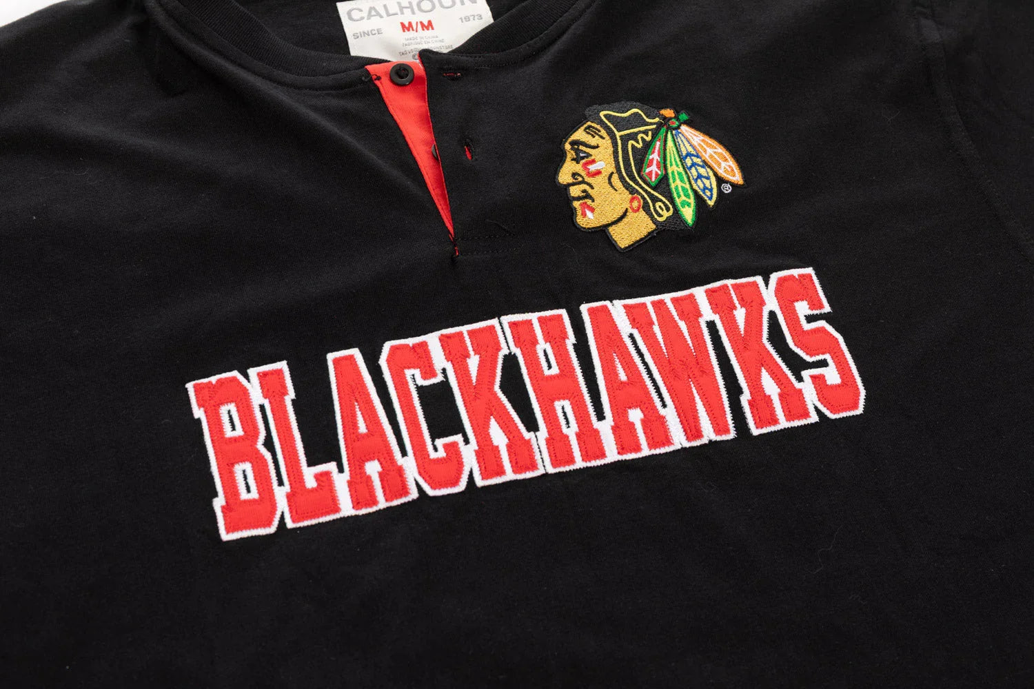 Black Chicago Blackhawks Henley shirt detail with embroidered logo and red lettering