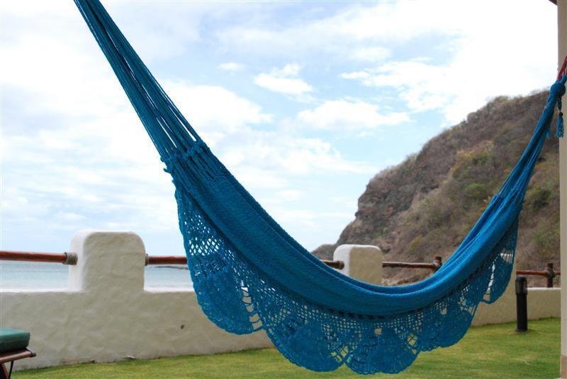 Blue crochet hammock on patio with ocean view and rocky hillside