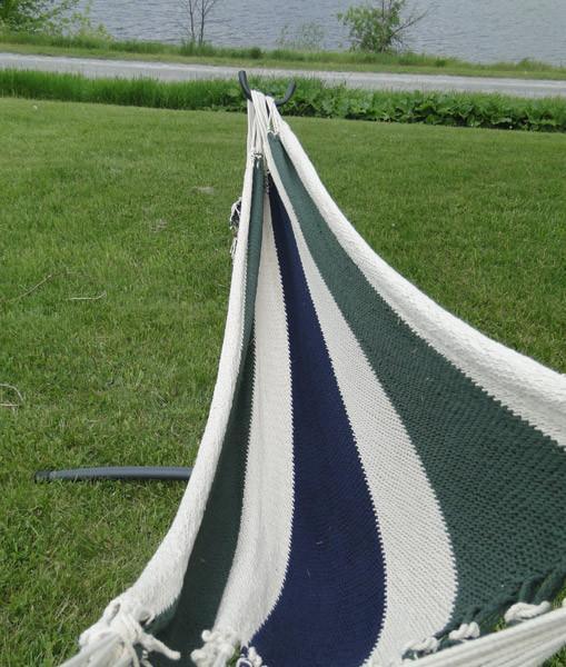 Striped hammock on stand outdoors, Nicaragua style, on green grass near water