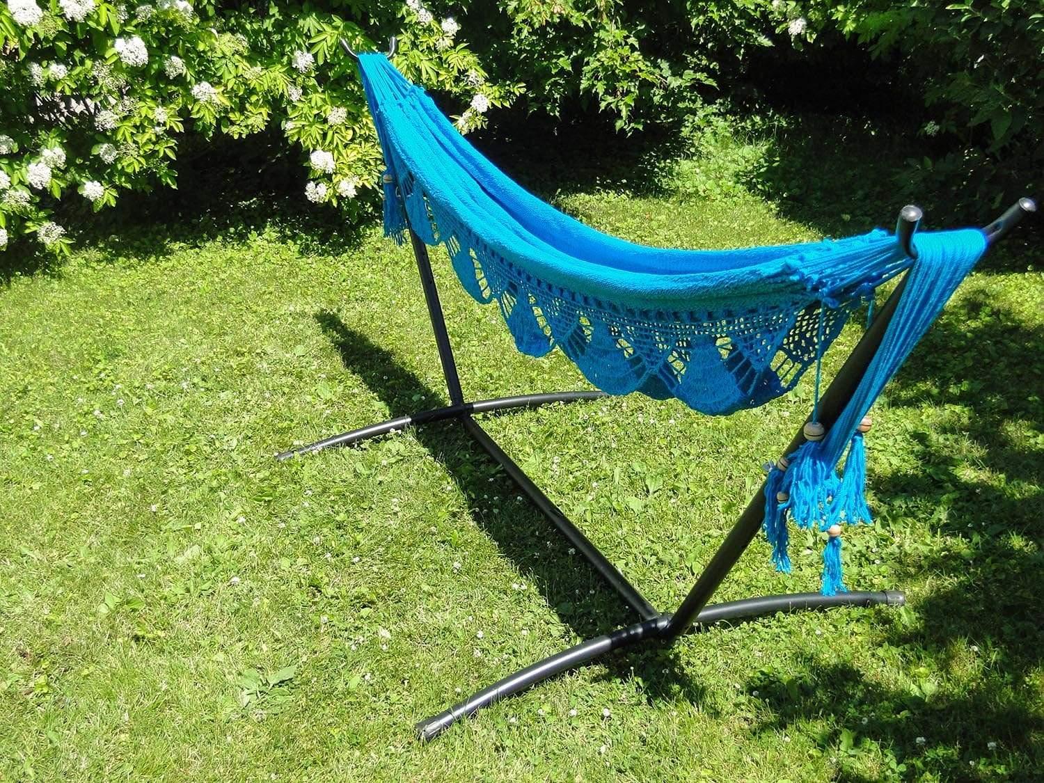 Blue Nicaraguan hammock on black metal stand in a sunny green garden