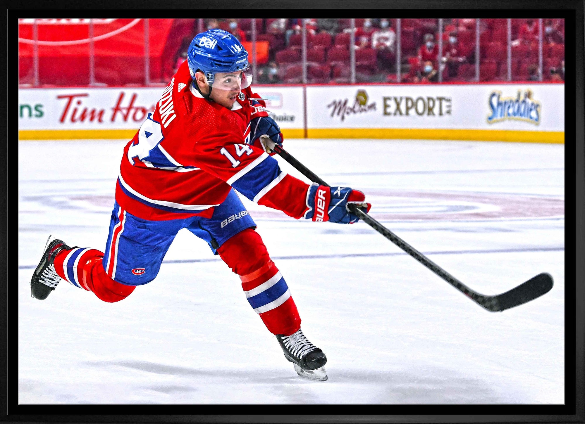 Ice hockey player in red Montreal Canadiens uniform shooting puck on ice rink