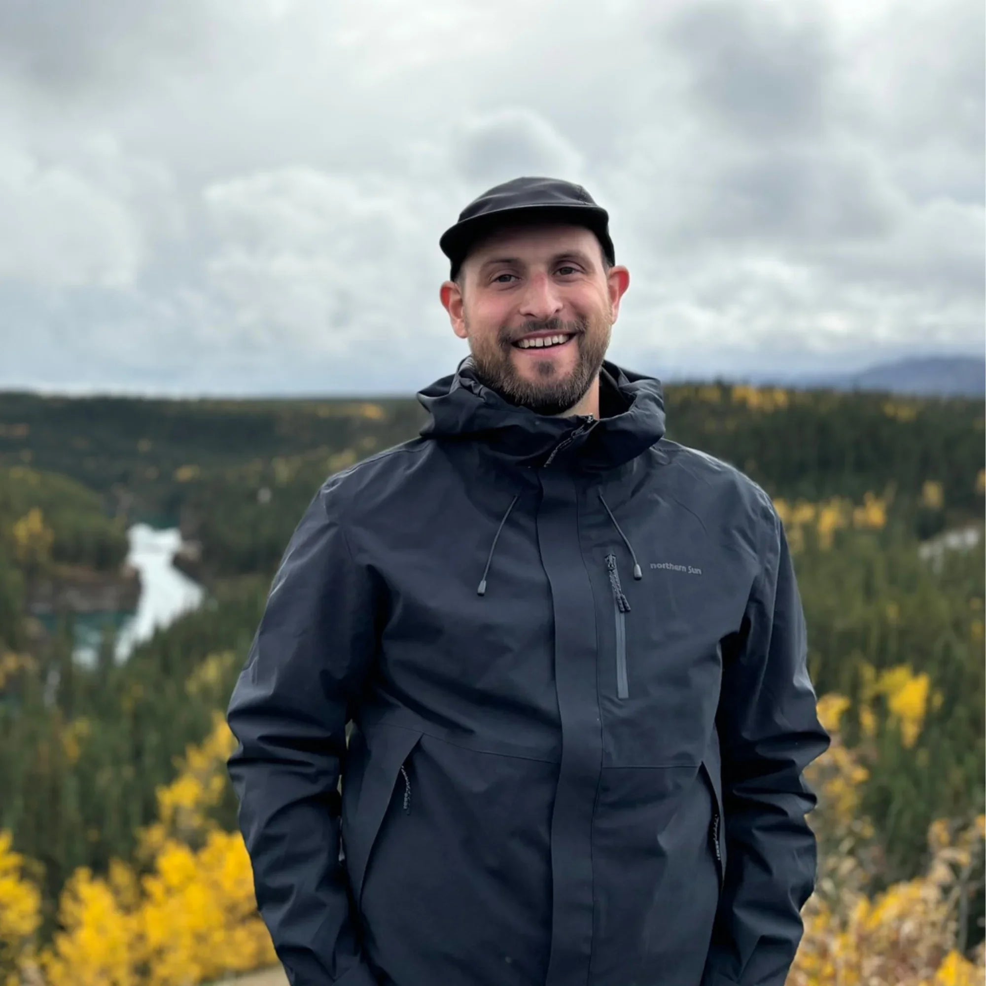 Man wearing Northern Sun 3-in-1 men's fall waterproof jacket outdoors in forested area