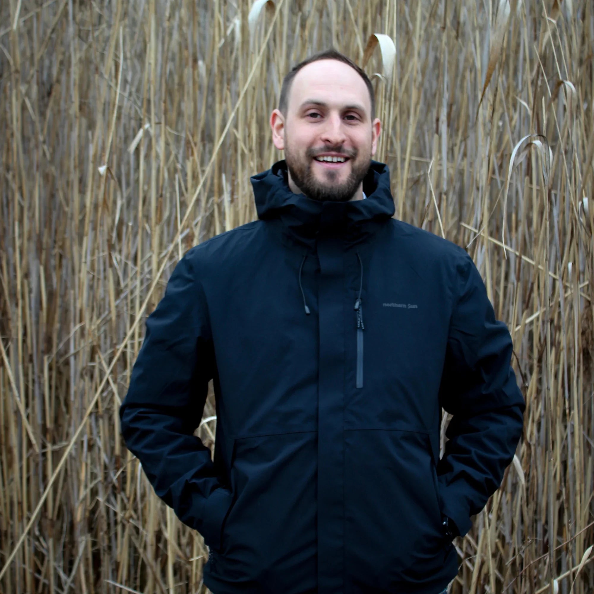 Man wearing Northern Sun 3-in-1 men's fall hiking jacket in tall dry grass outdoors