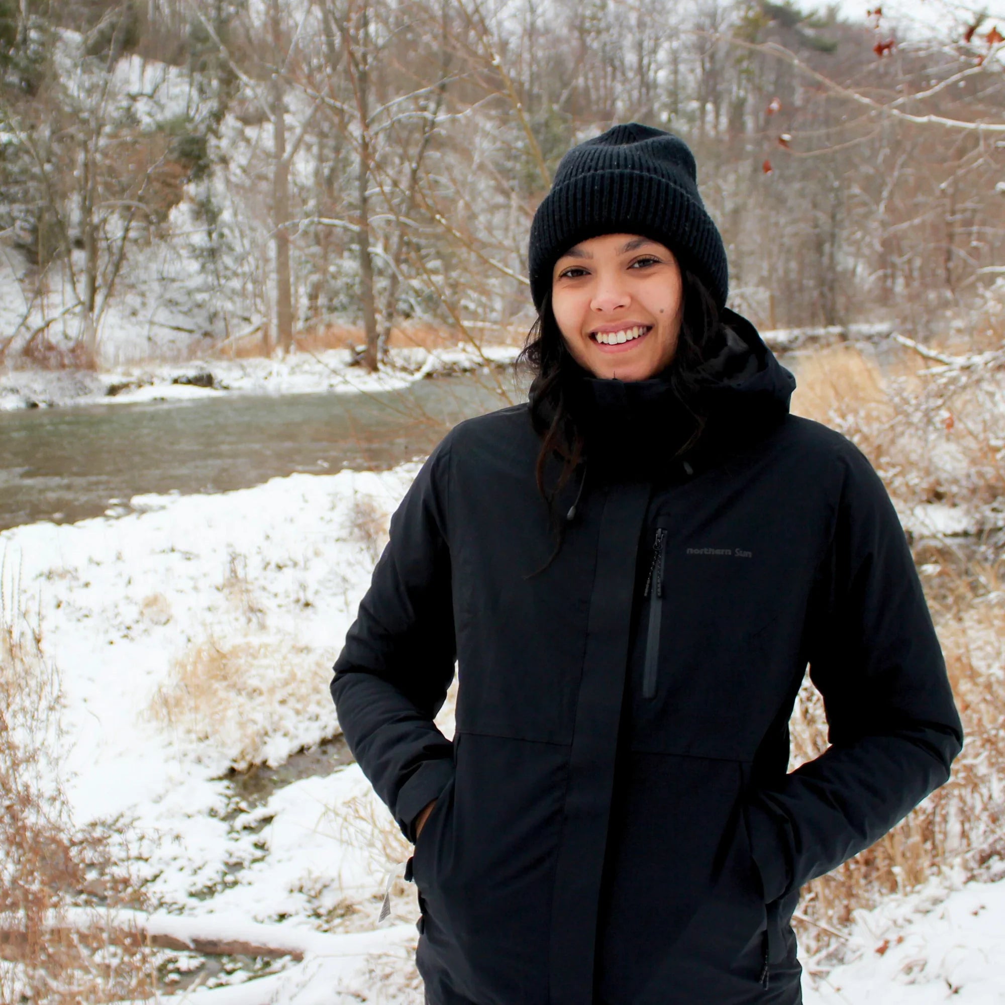 Woman wearing black winter waterproof 3-in-1 jacket outdoors in snowy landscape
