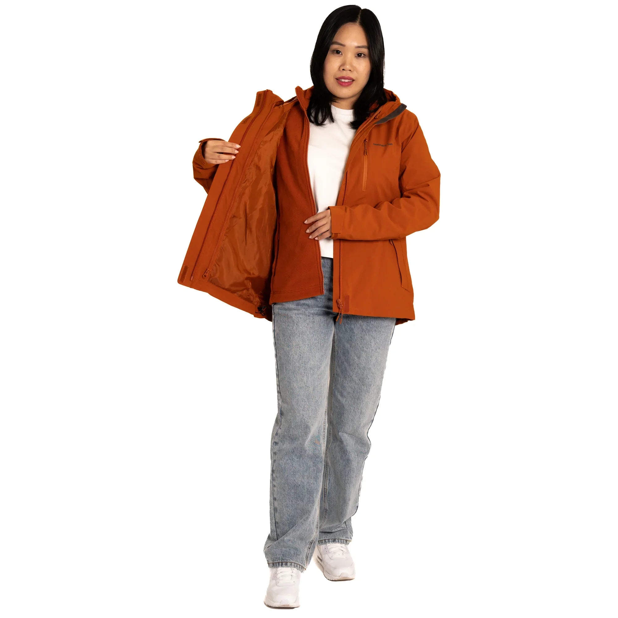 Woman modeling orange hooded jacket, white shirt, blue jeans, and white sneakers