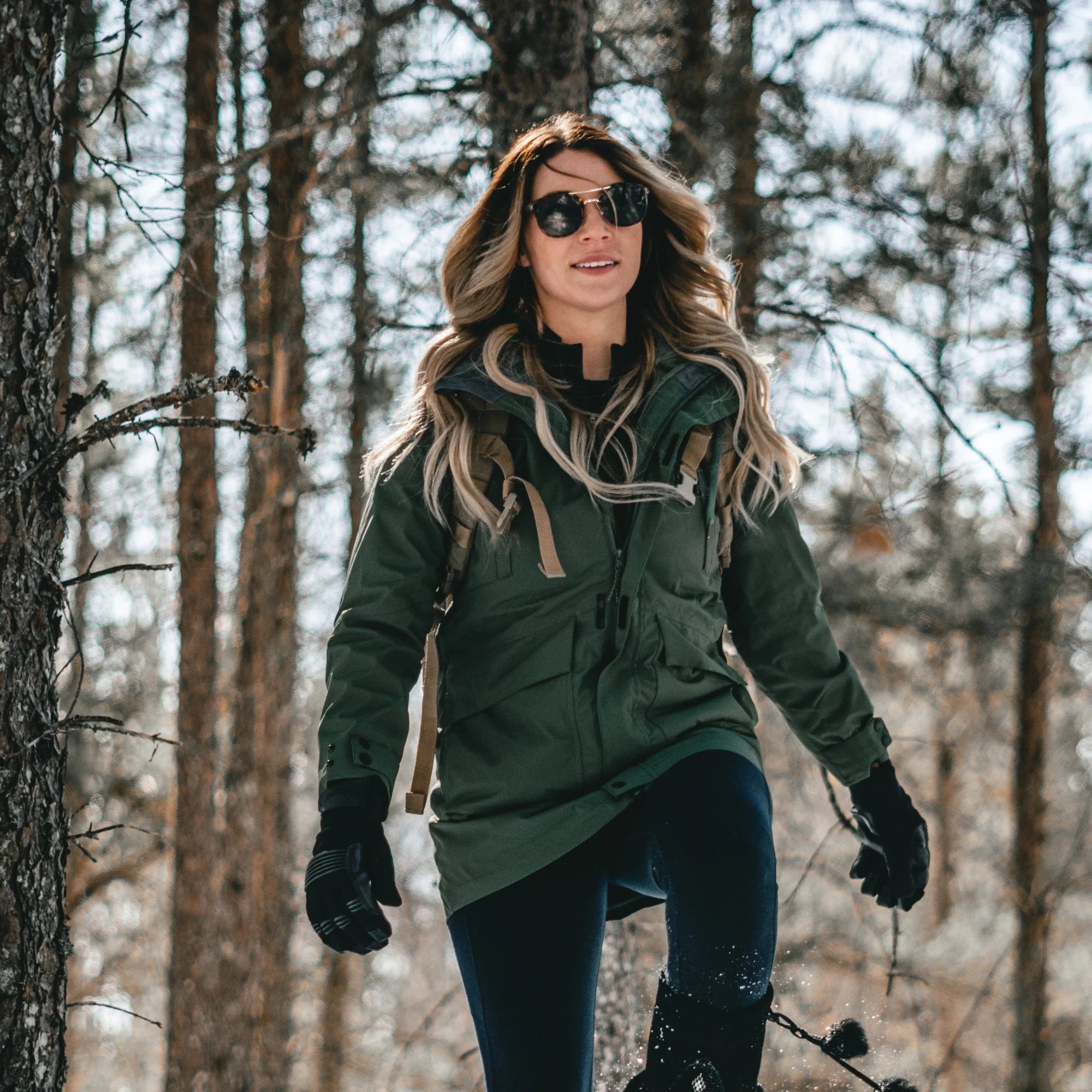 Woman hiking in forest wearing forest green 3-in-1 waterproof winter jacket