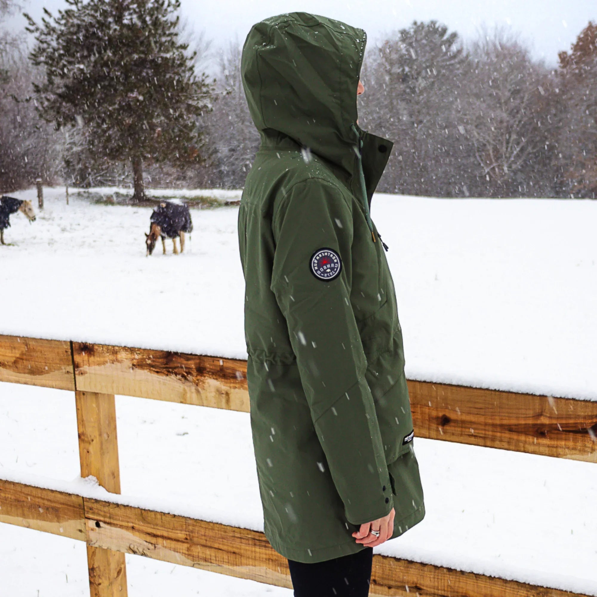 Woman in forest green 3-in-1 winter coat standing in snowy Canada outdoor scene