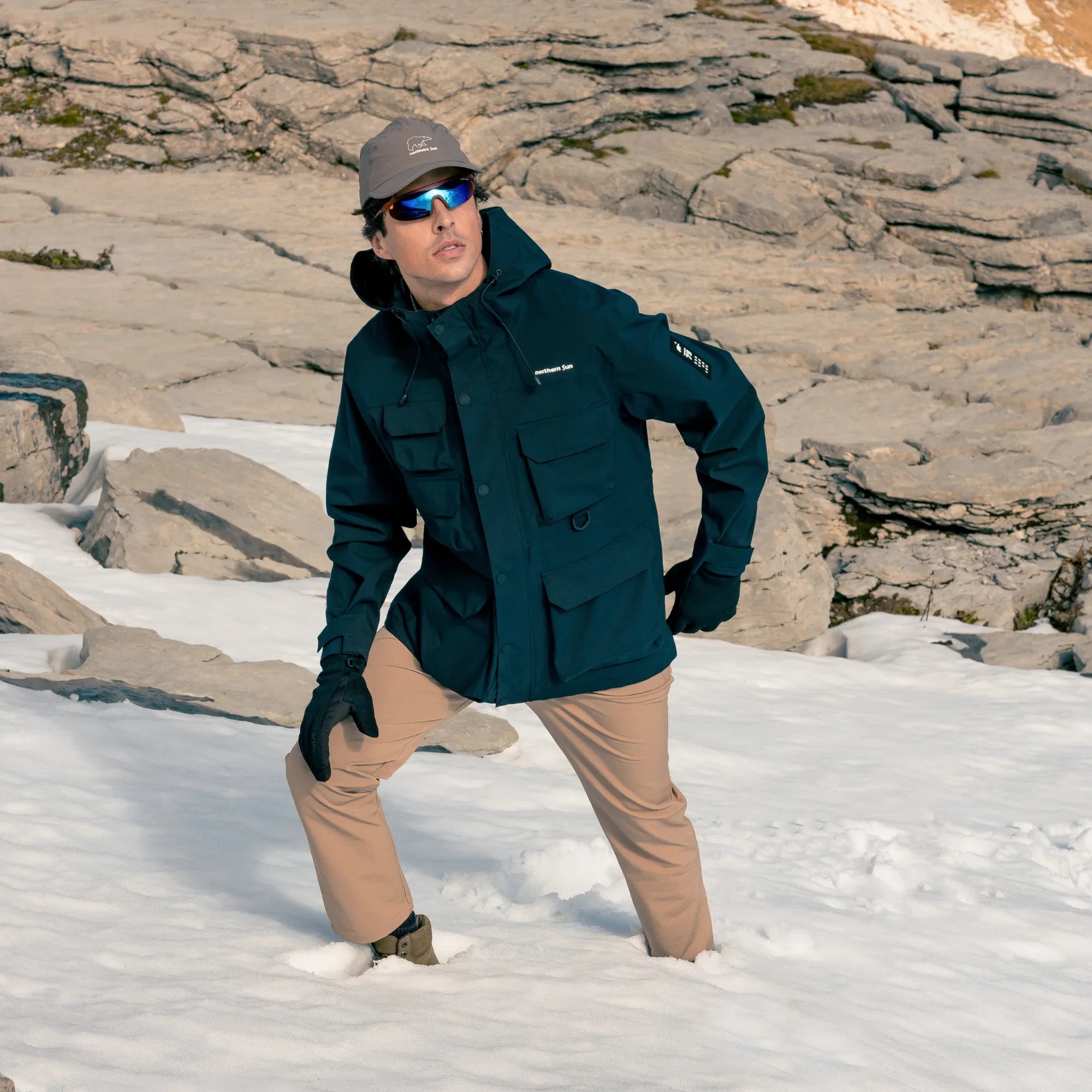 Man wearing Northern Sun men's 3-in-1 parka in snow with rocky mountain background