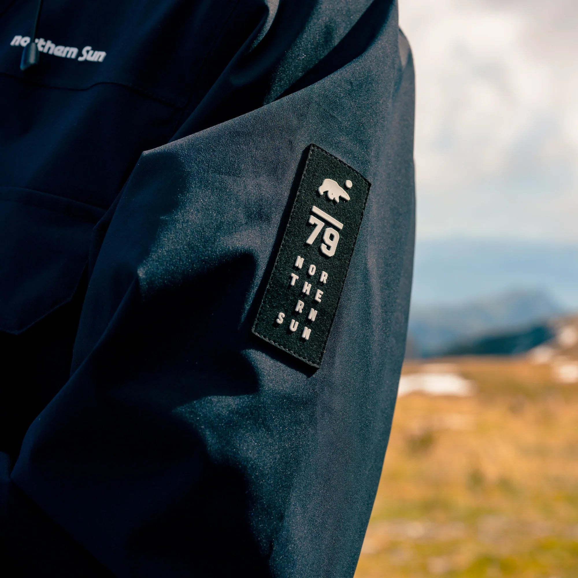 Northern Sun men's parka sleeve with logo patch, outdoors in Canadian mountains