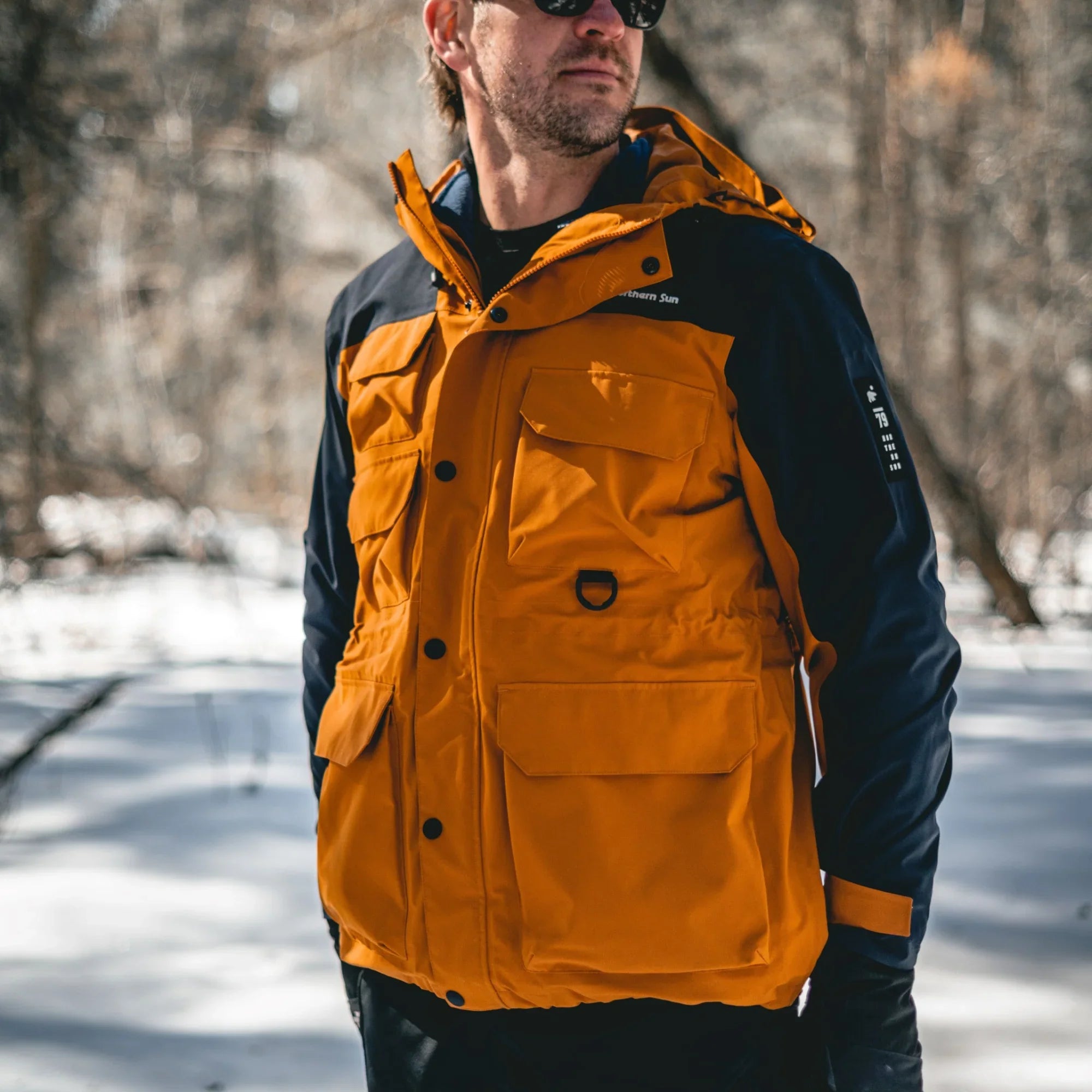 Man wearing Northern Sun men's orange and blue winter parka jacket outdoors in snow
