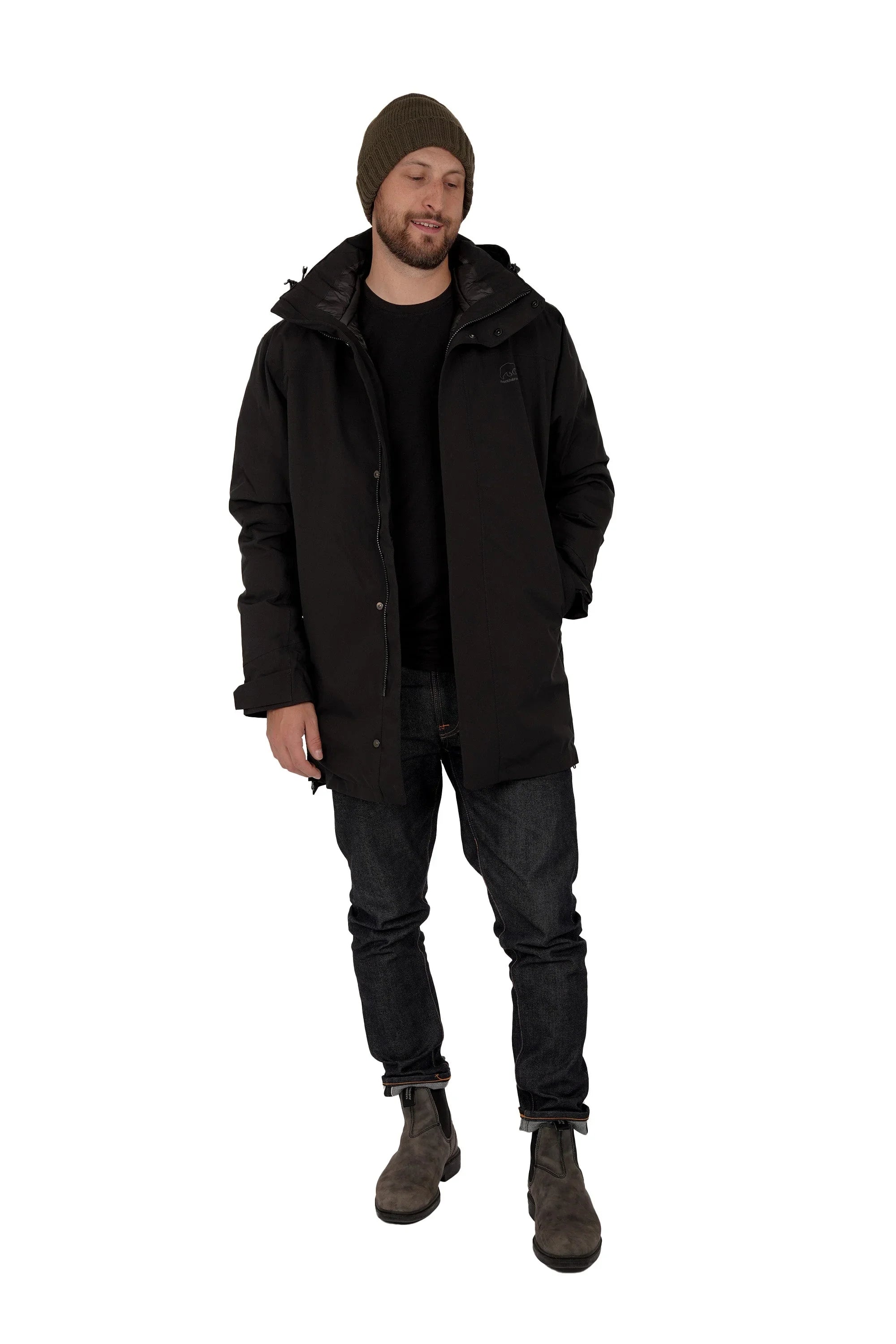Man wearing black parka, beanie, jeans, and boots on white background