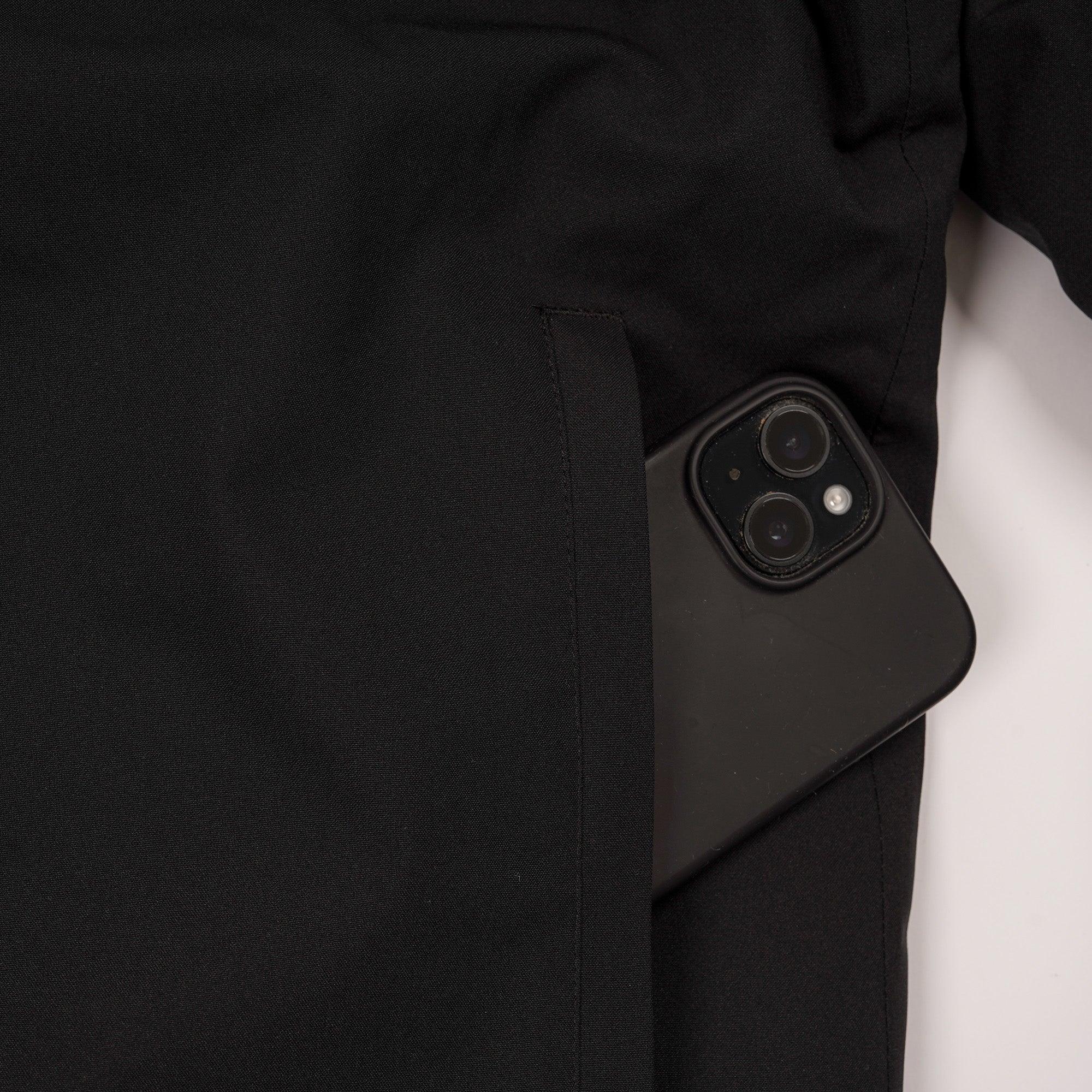 Black smartphone partially inside black jacket pocket, close-up detail shot