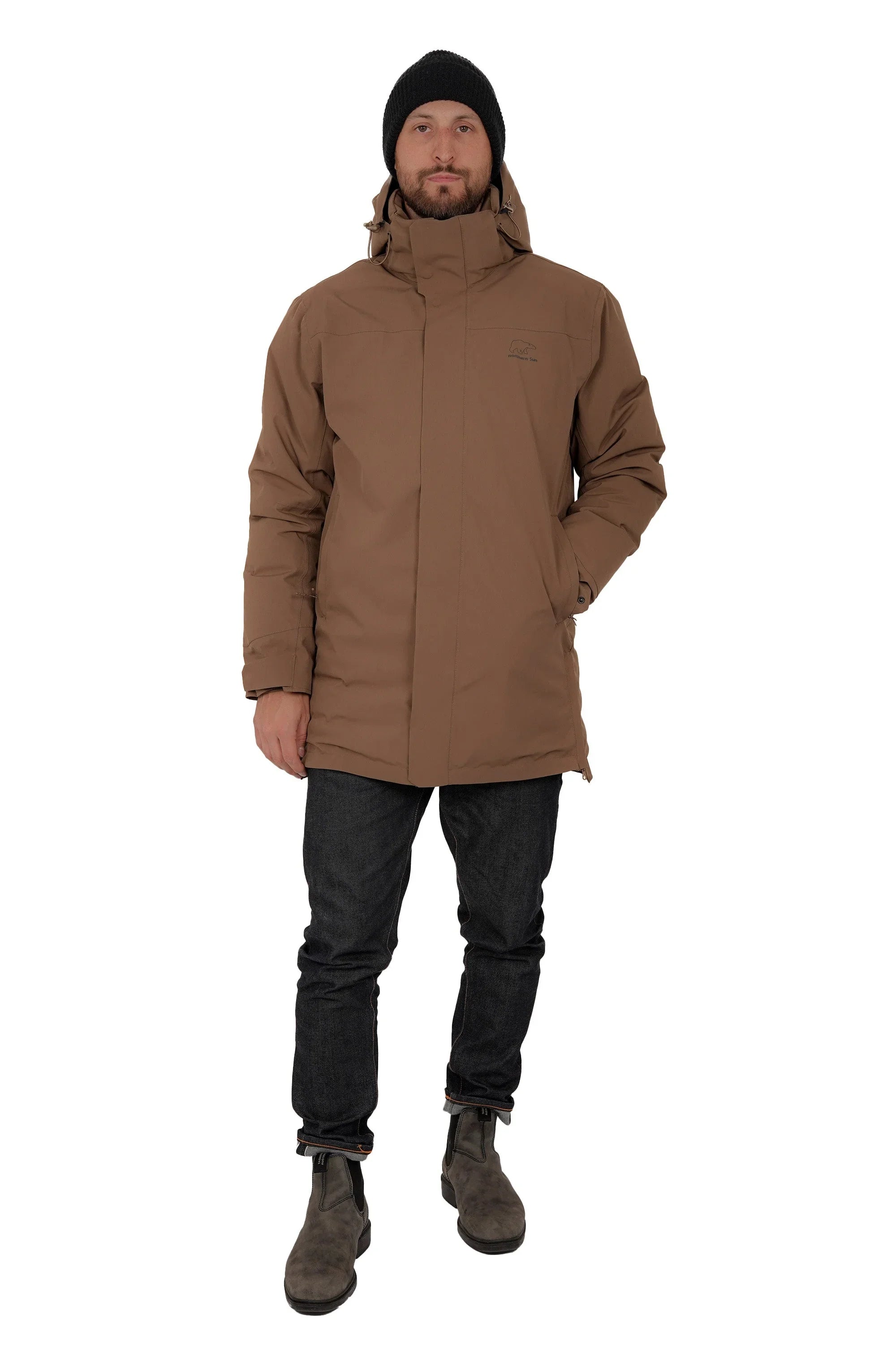 Man wearing brown winter parka jacket, black beanie, dark jeans, and boots on white background