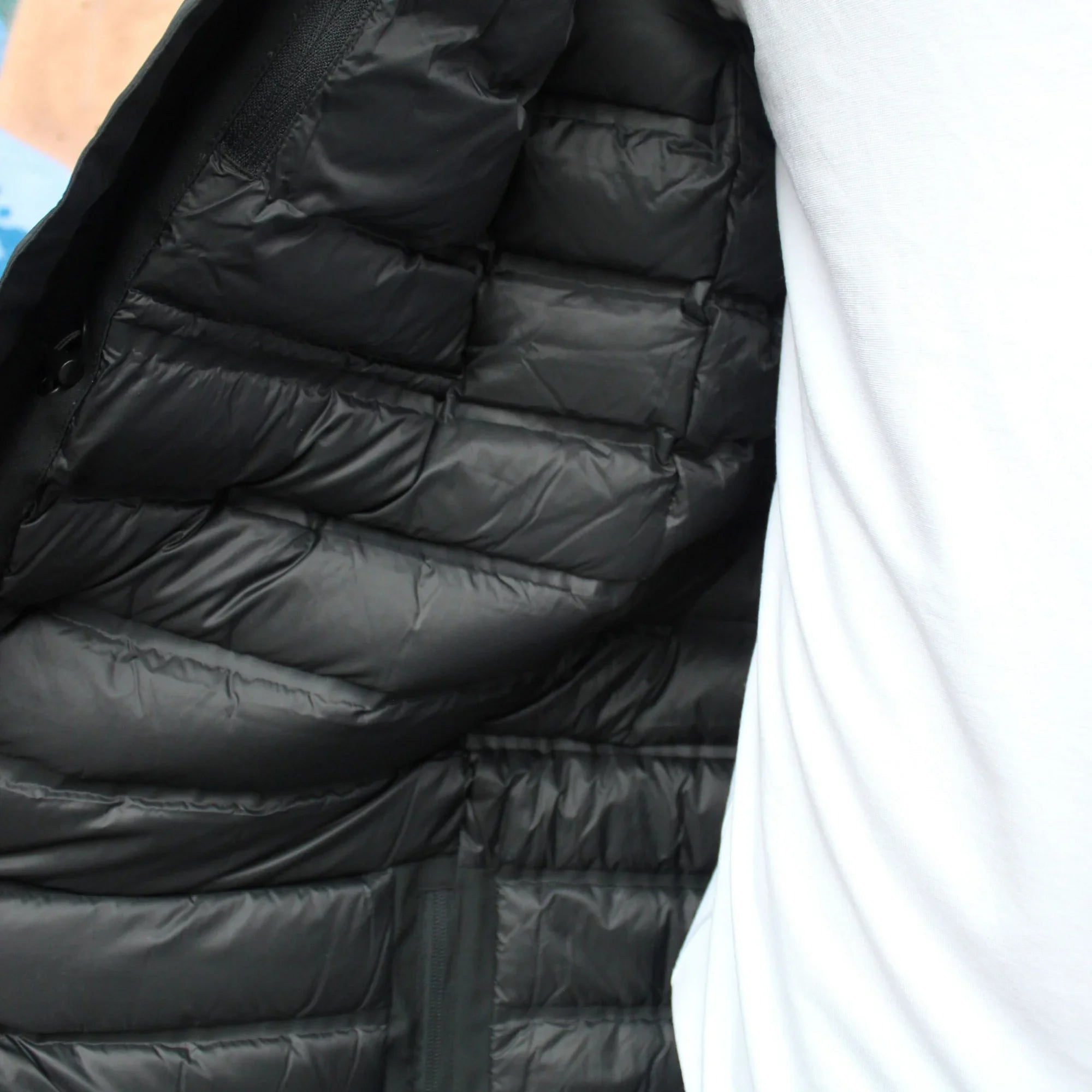 Inside view of black puffer jacket against a white shirt