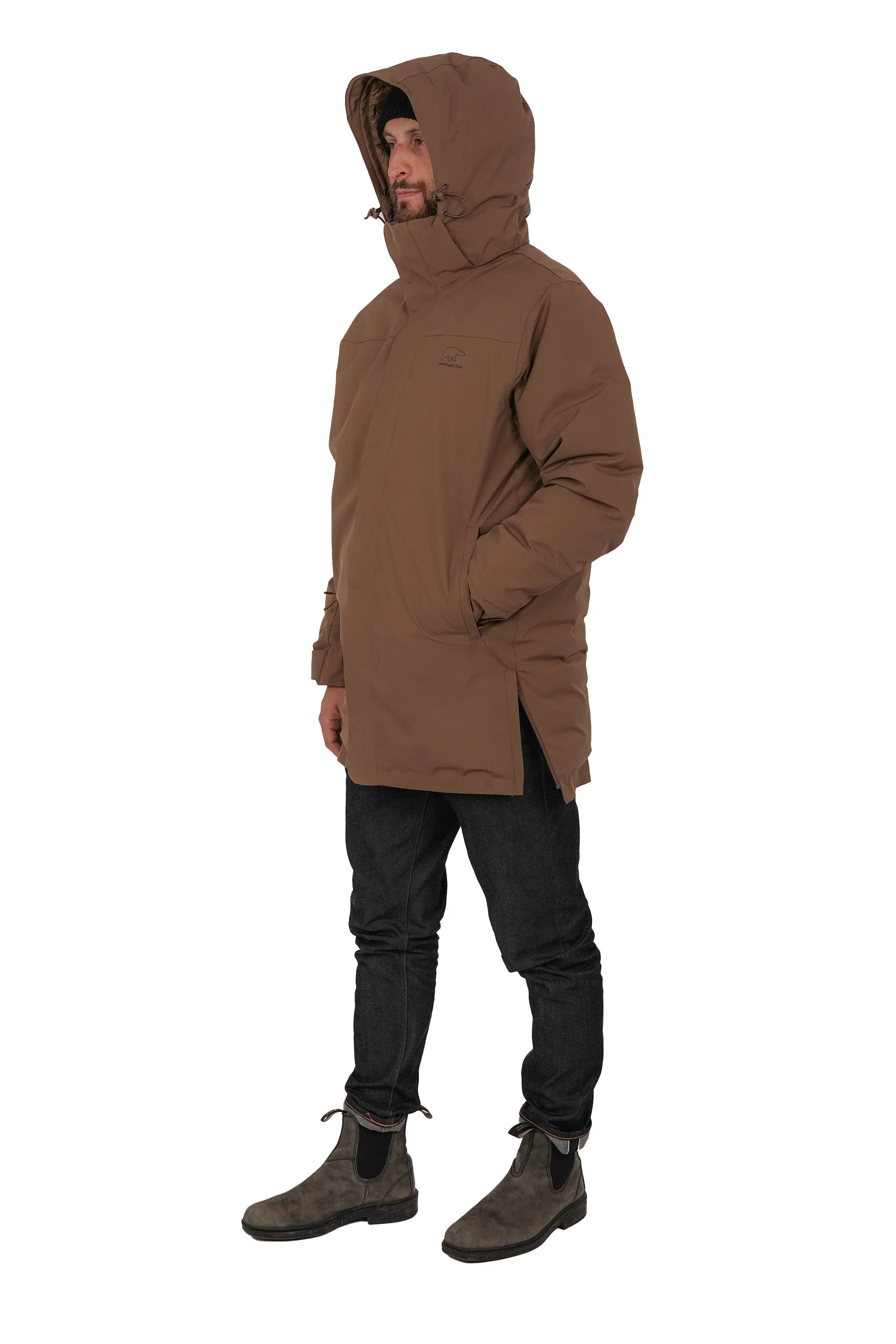 Man wearing brown hooded winter parka, black jeans, grey boots on white background