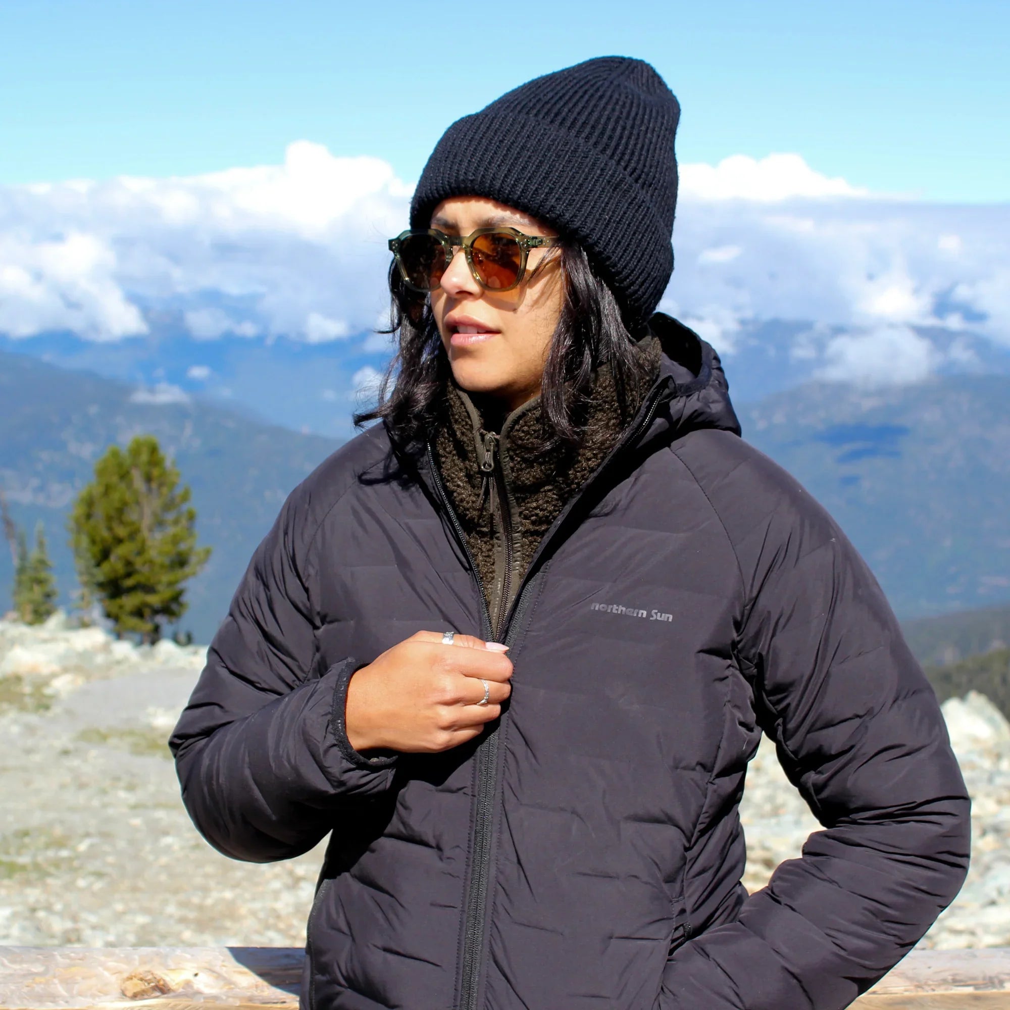 Woman wearing Northern Sun Dawson lightweight down jacket and beanie outdoors in mountains