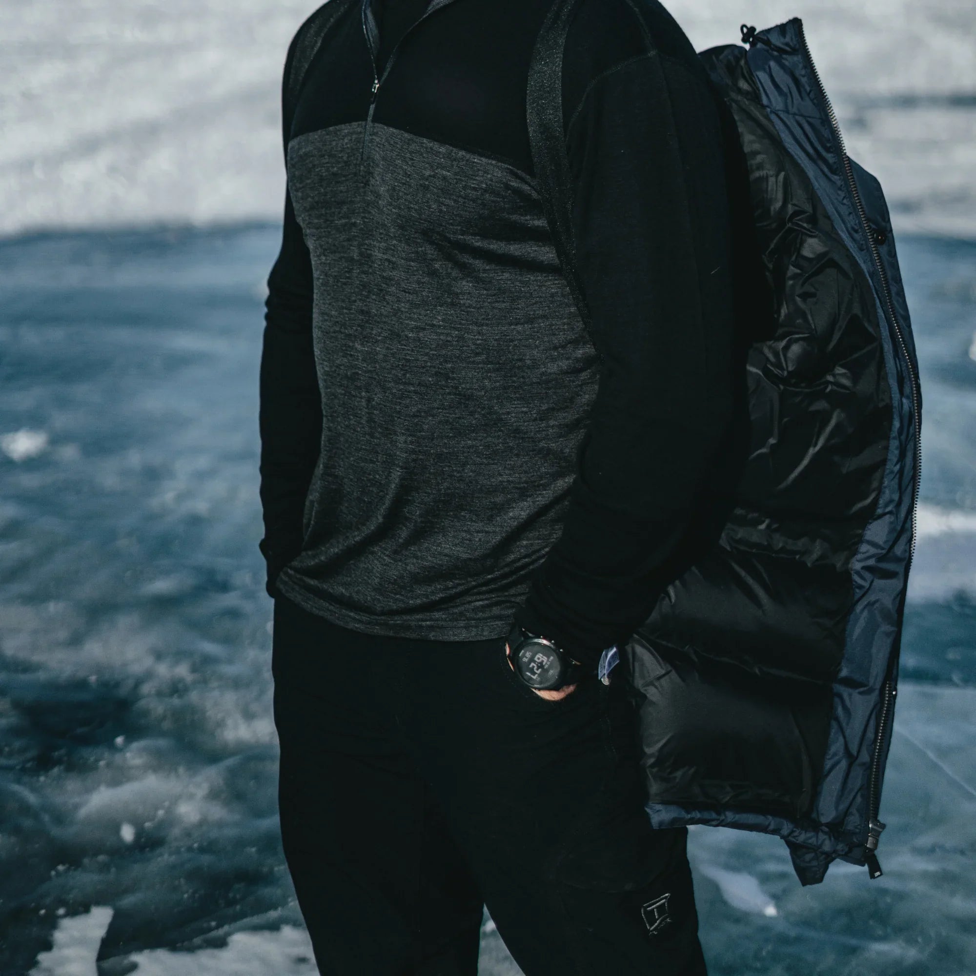 Man outdoors wearing Northern Sun men's winter down parka with shoulder straps on ice