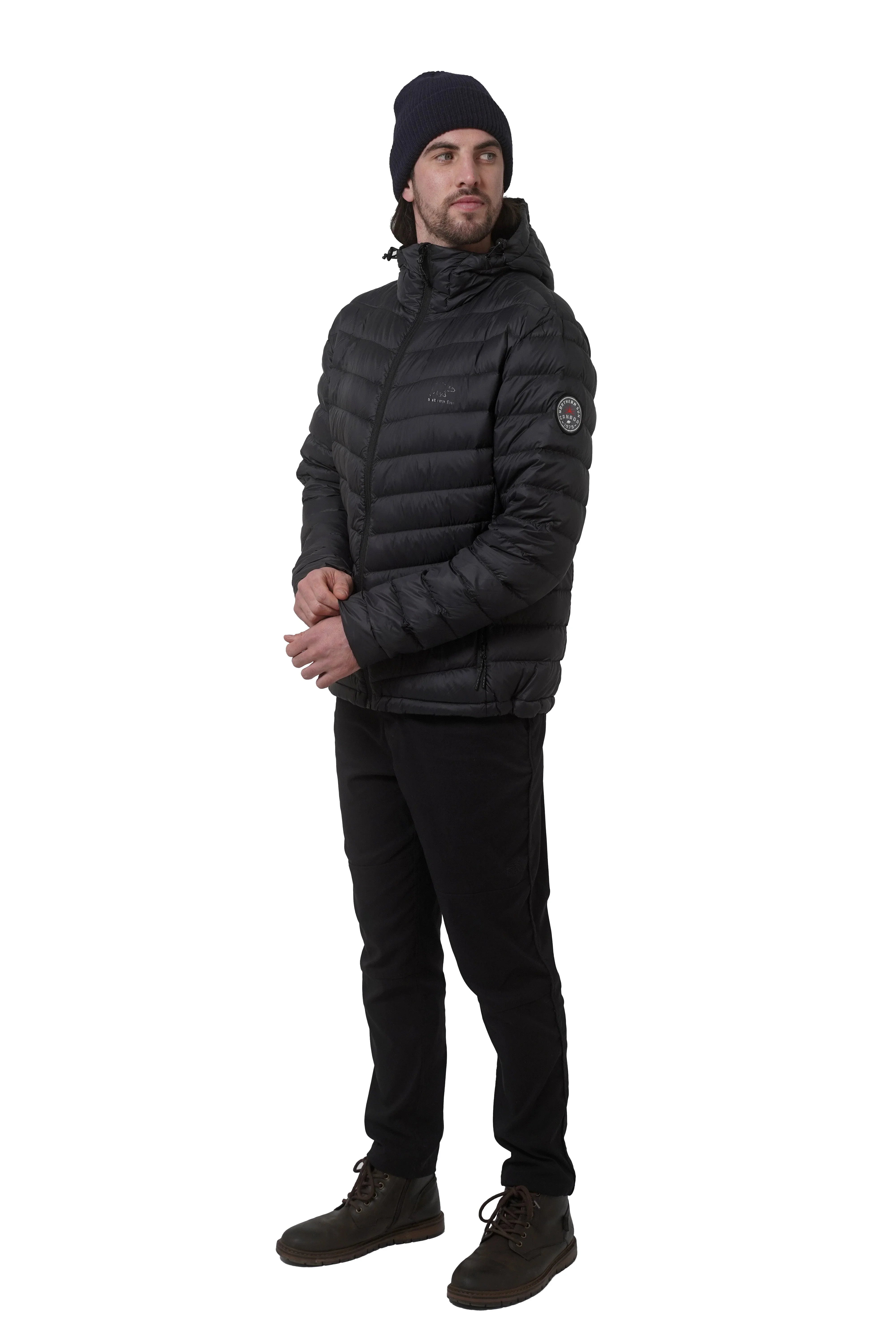 Man wearing black lightweight packable down jacket, black pants, beanie, and boots
