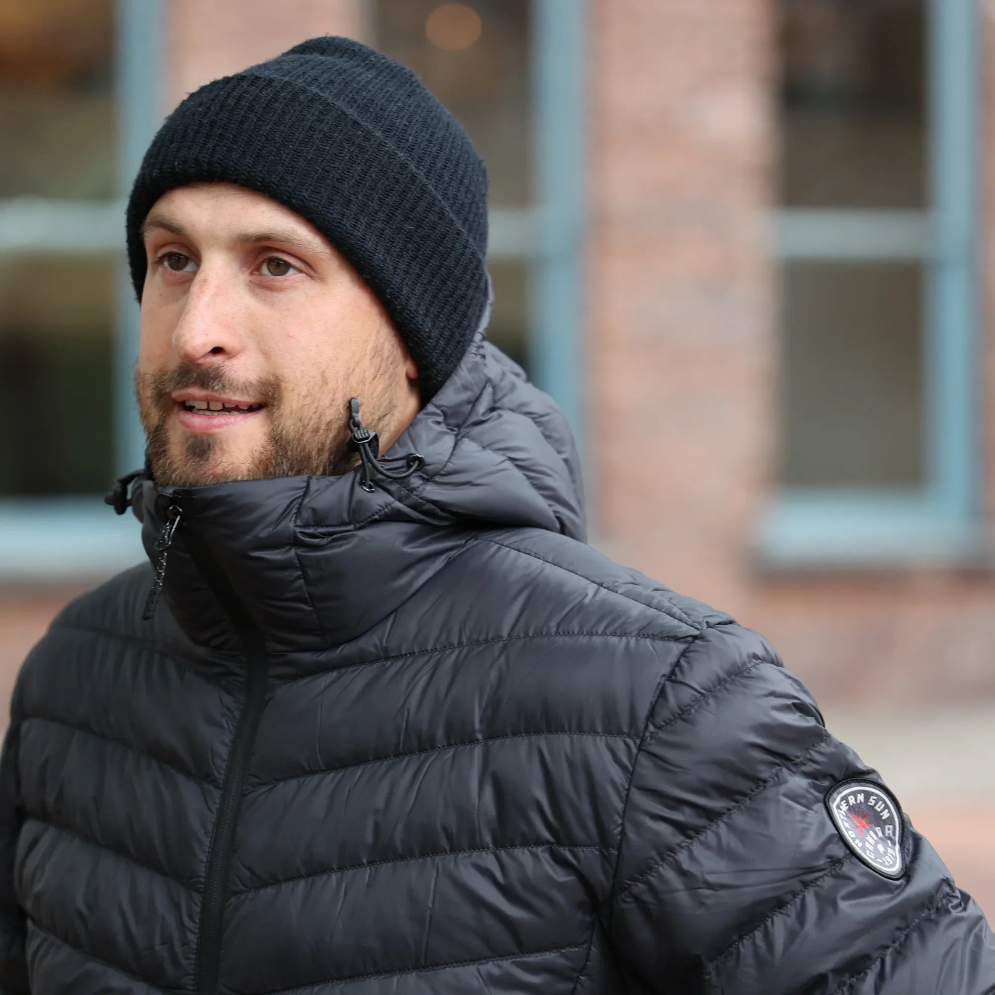 Man wearing black Northern Sun men's lightweight packable down jacket outdoors