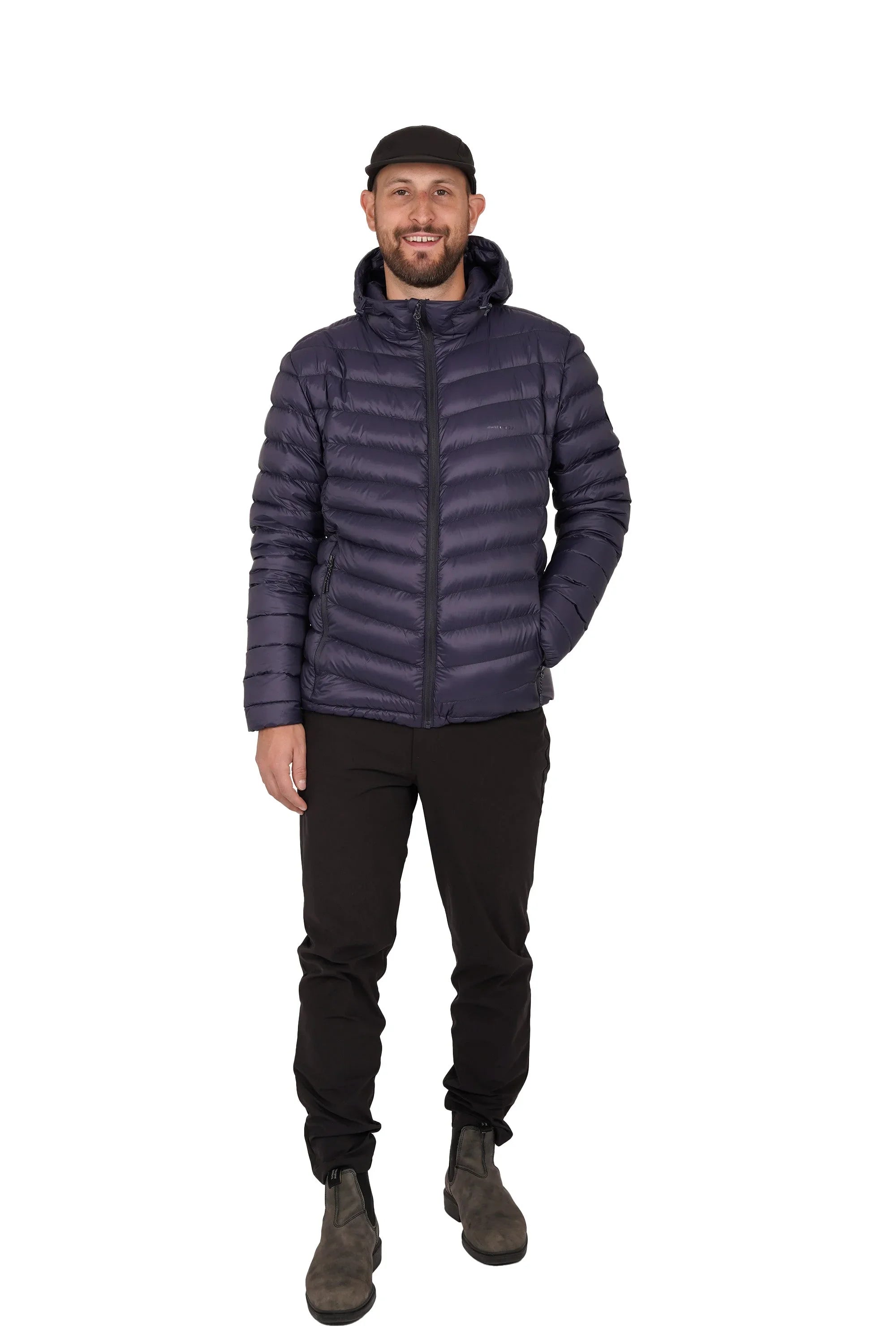 Man wearing navy lightweight packable down jacket, black pants, boots, and cap on white background