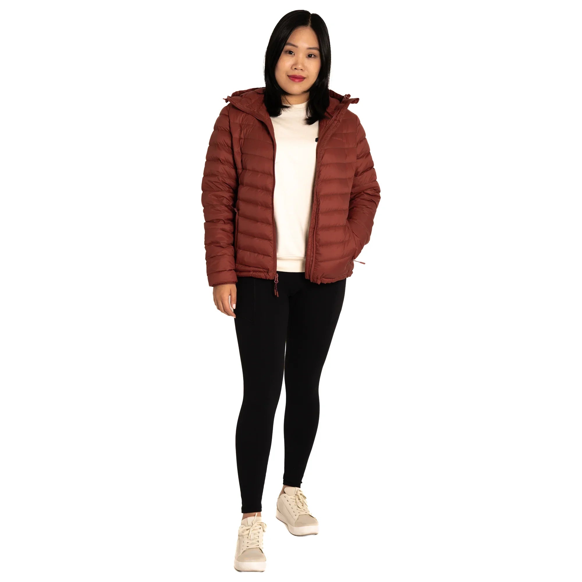 Woman wearing a brown puffer jacket, white shirt, black leggings, and sneakers