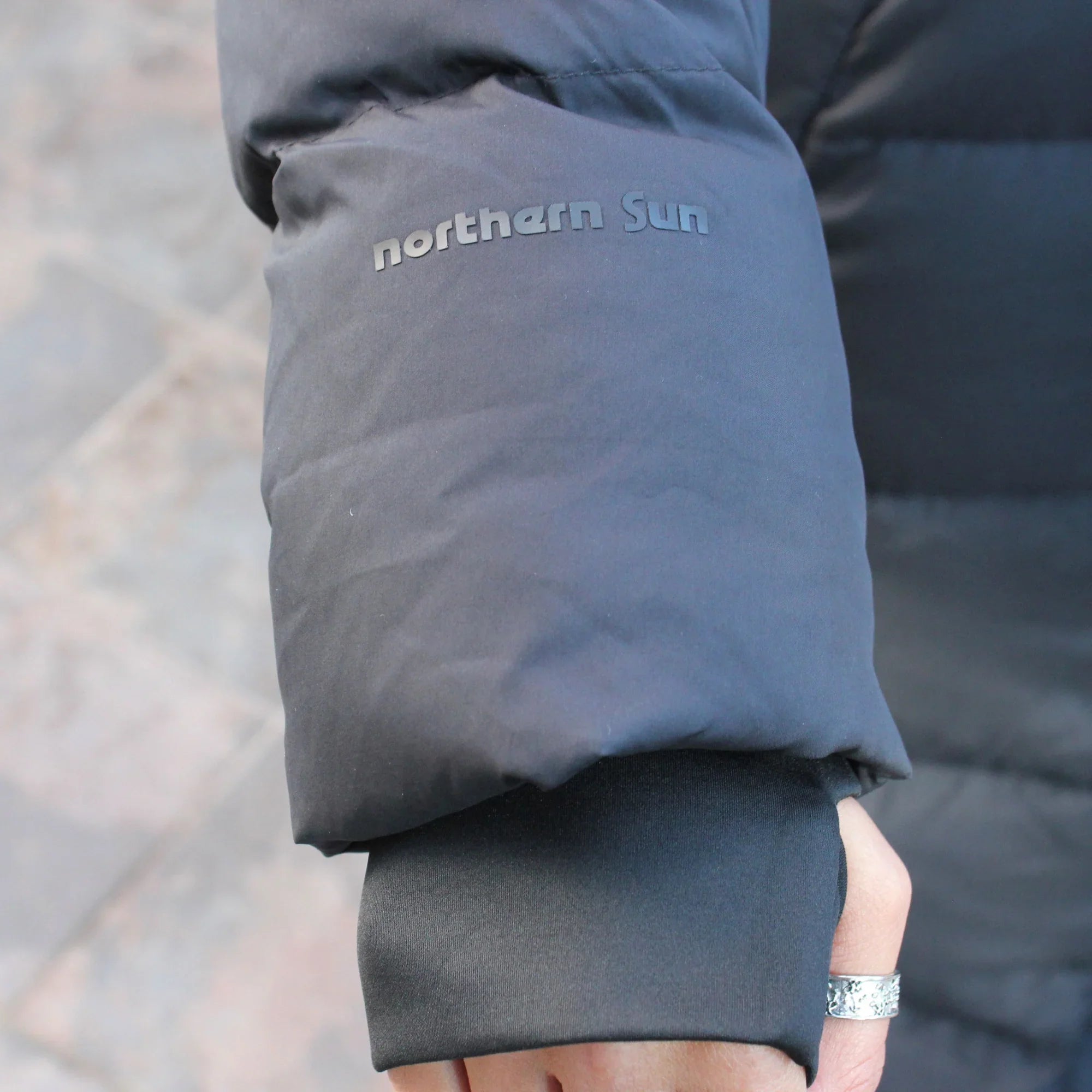 Close-up of Northern Sun black puffer jacket sleeve outdoors