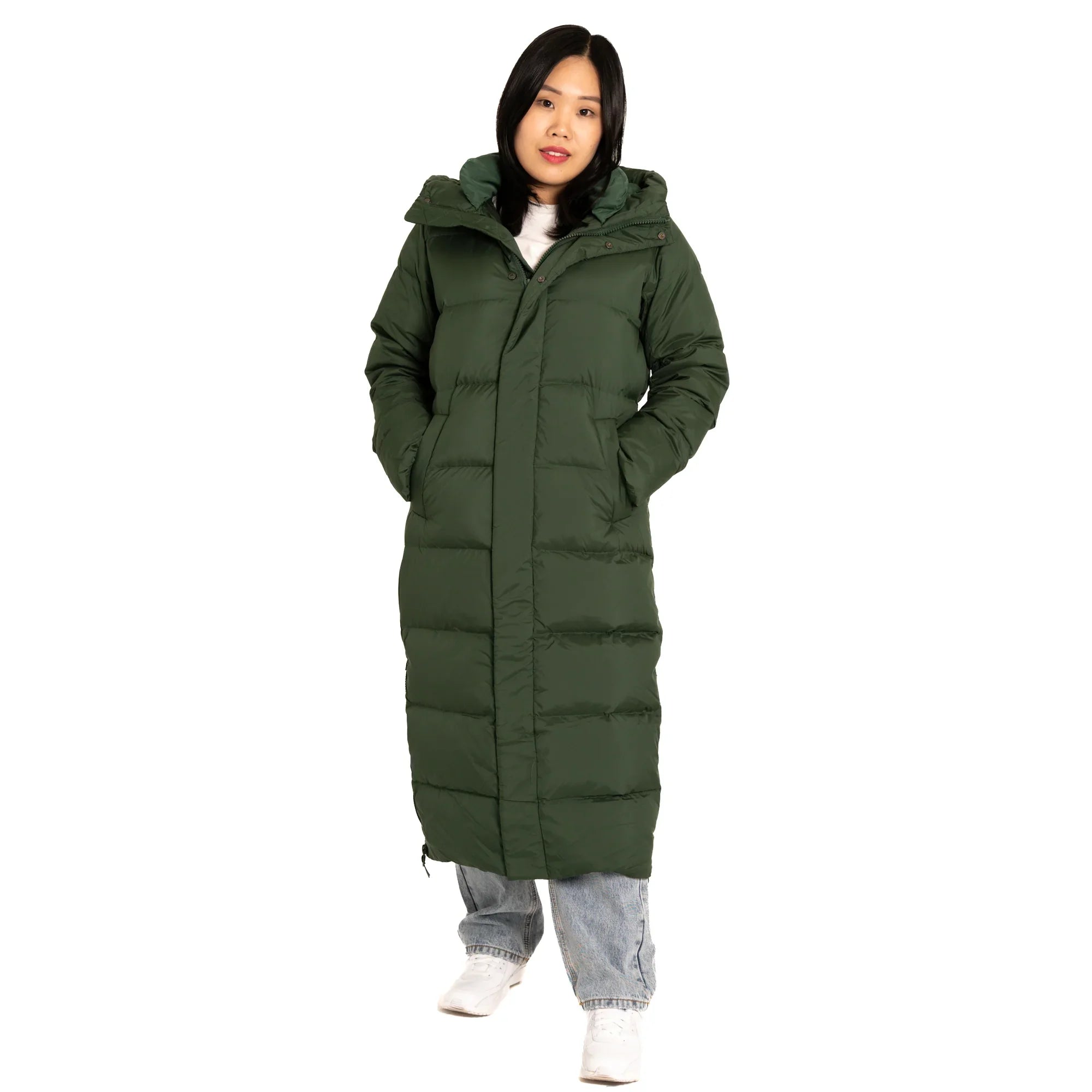 Woman wearing a long green puffer coat with hood, light jeans, and white sneakers