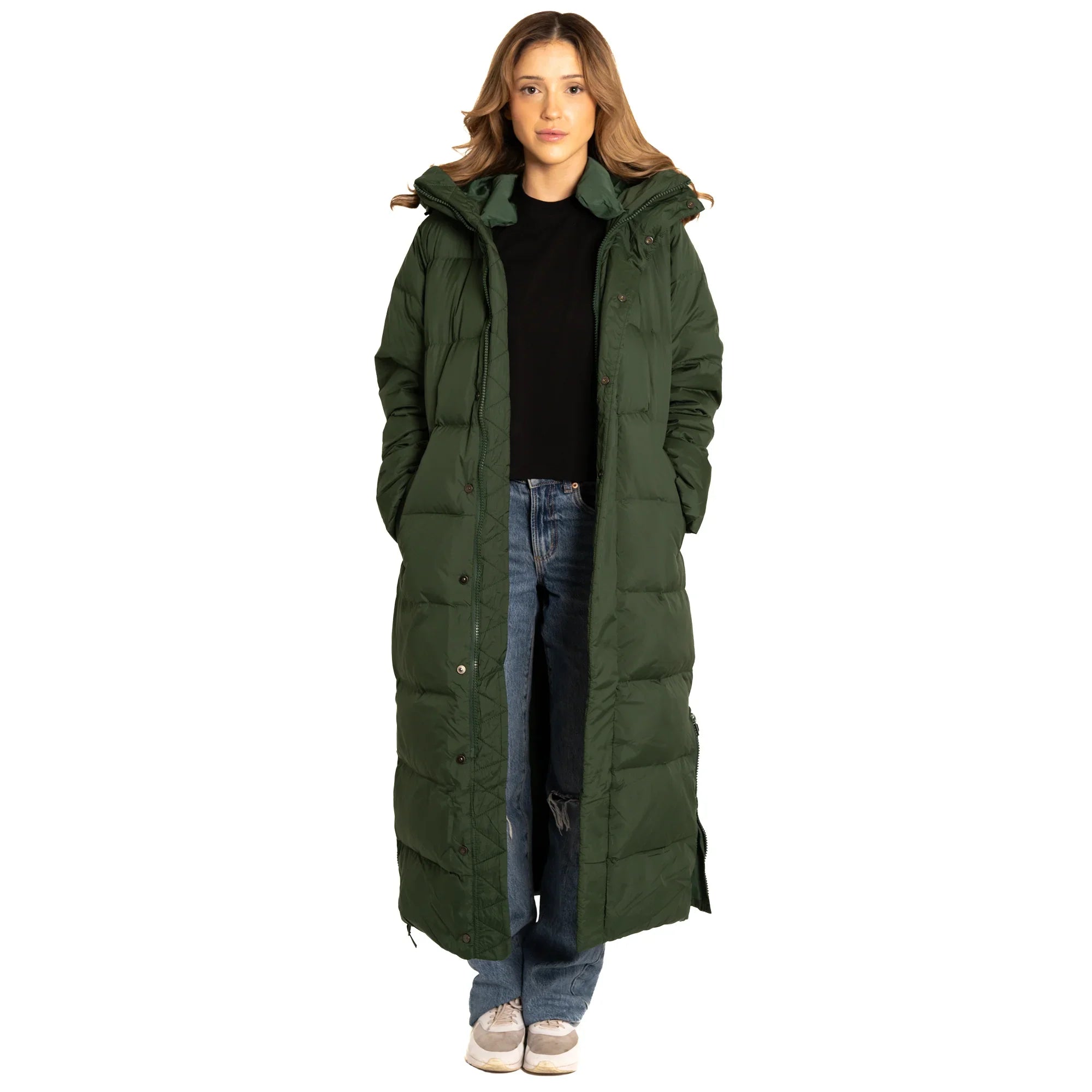 Woman wearing long green puffer coat, black top, blue jeans, white sneakers