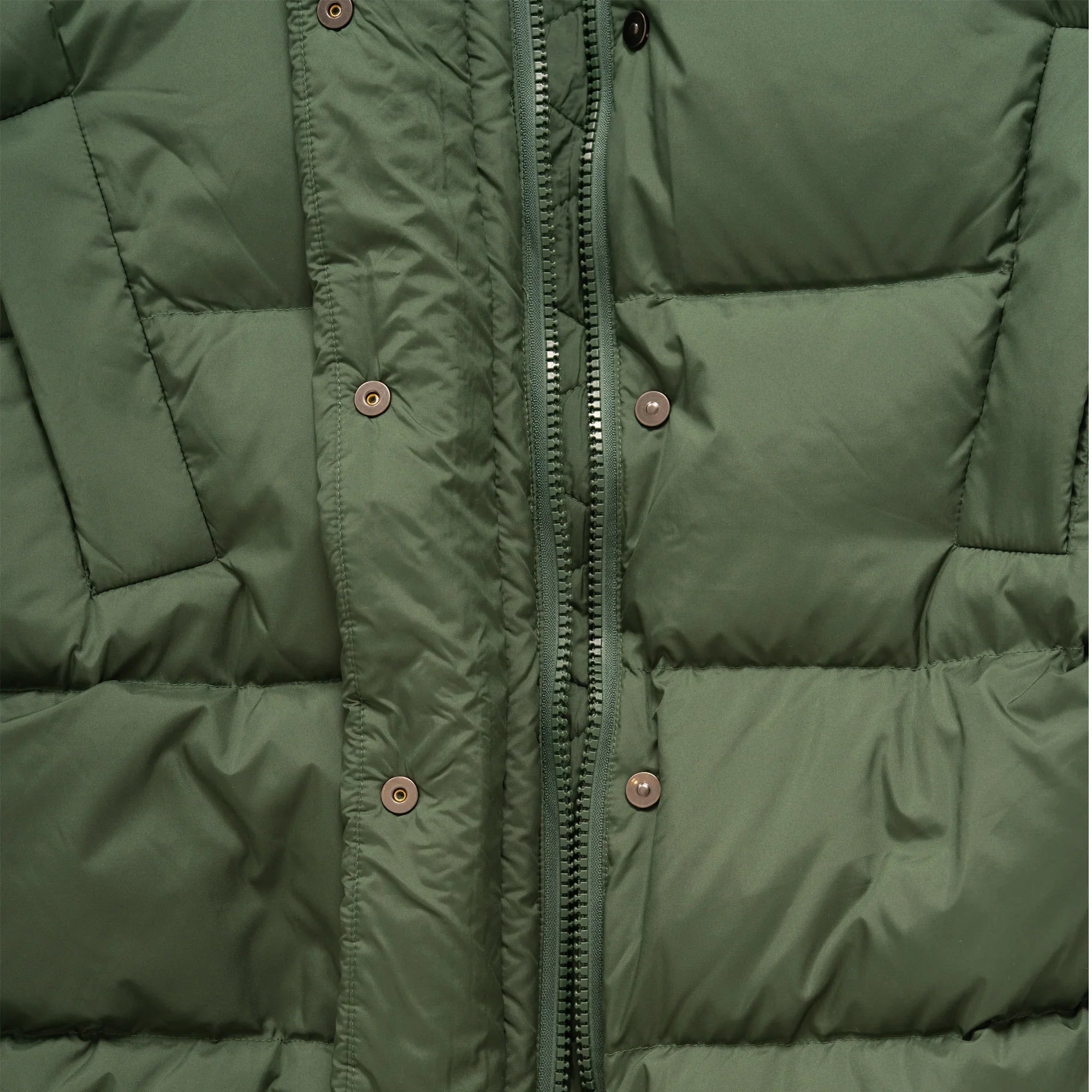 Close-up of green puffer jacket with quilted design, zipper, and snap buttons