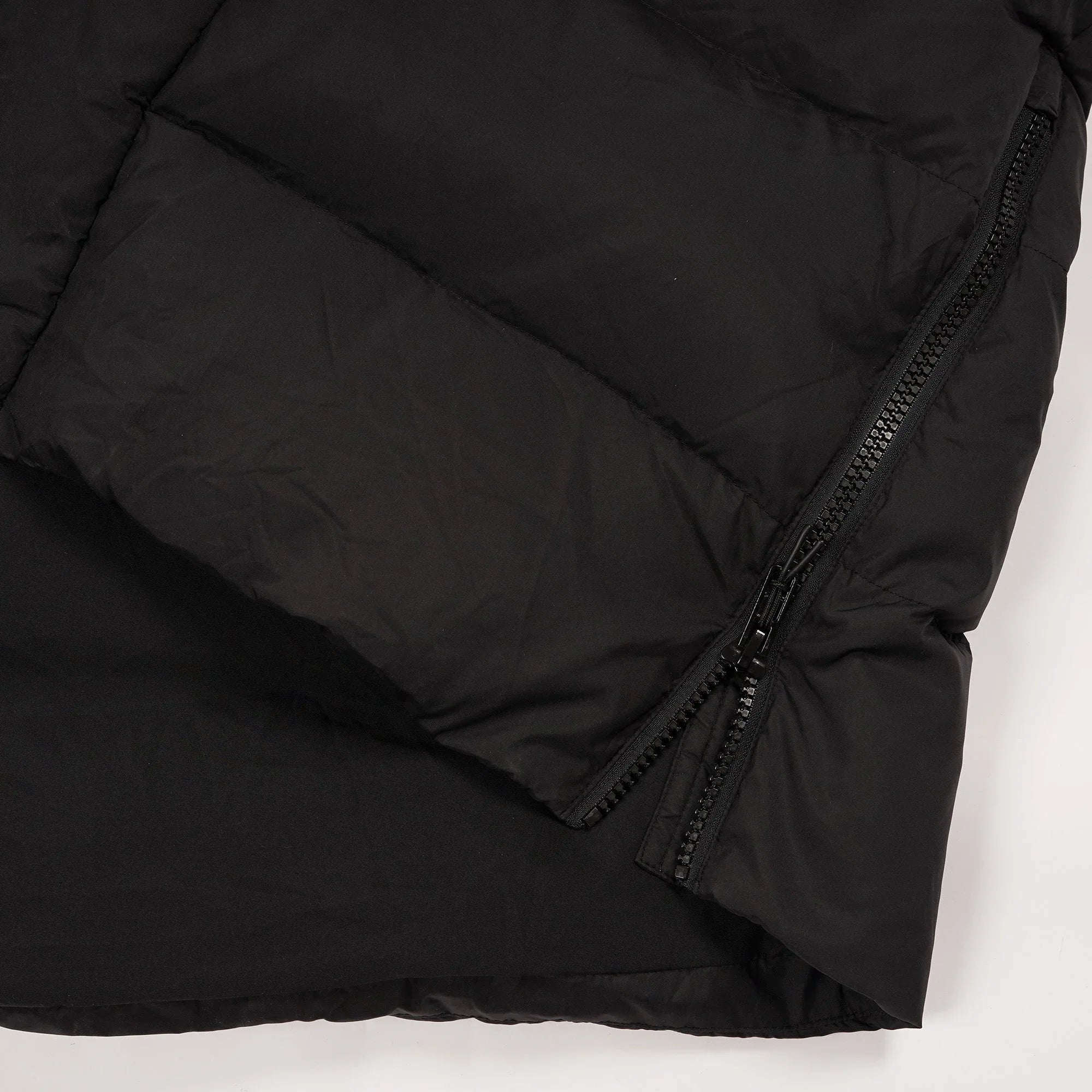 Close-up of black puffer jacket with diagonal zipper detail on fabric