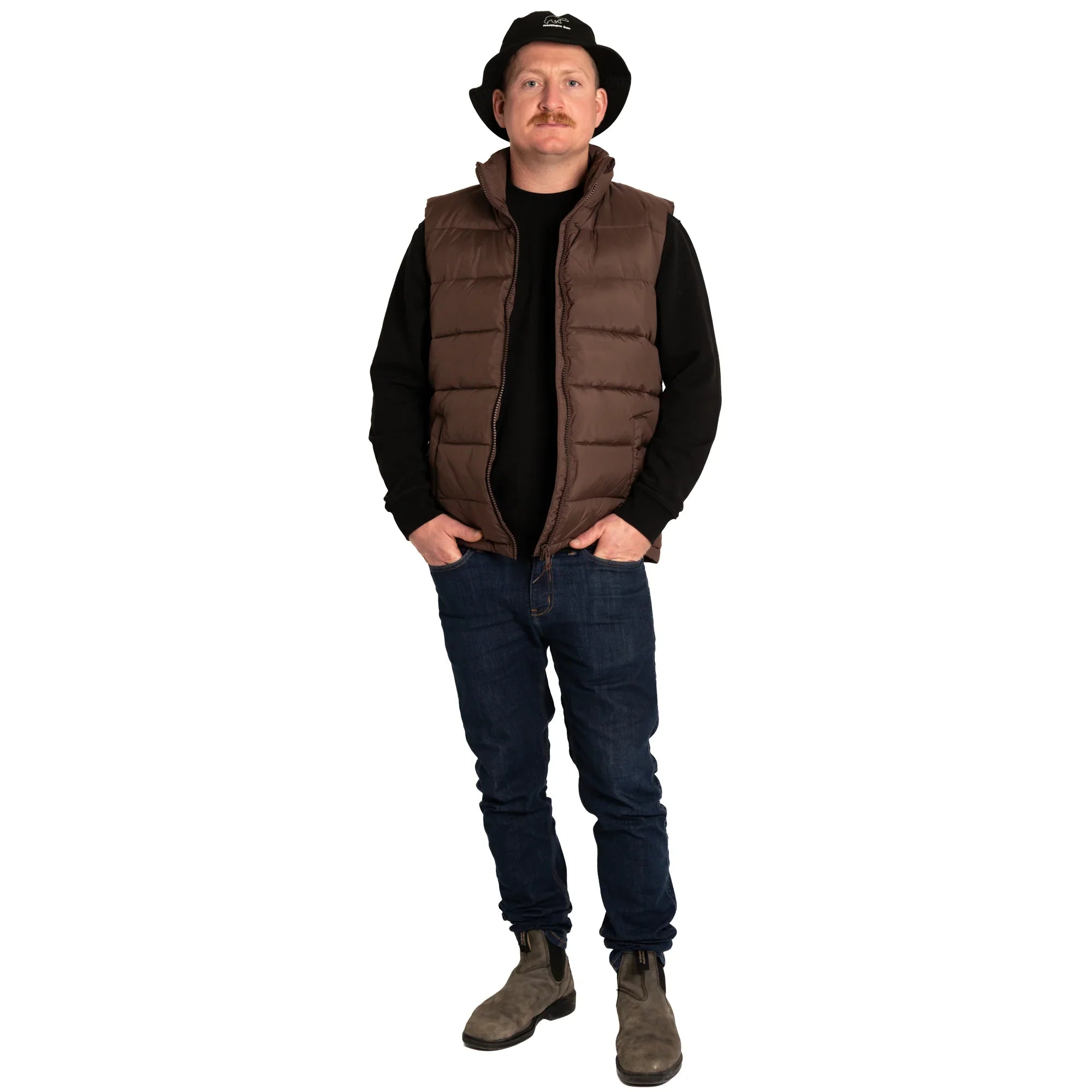 Man in brown puffer vest, black hat, jeans, and boots on white background