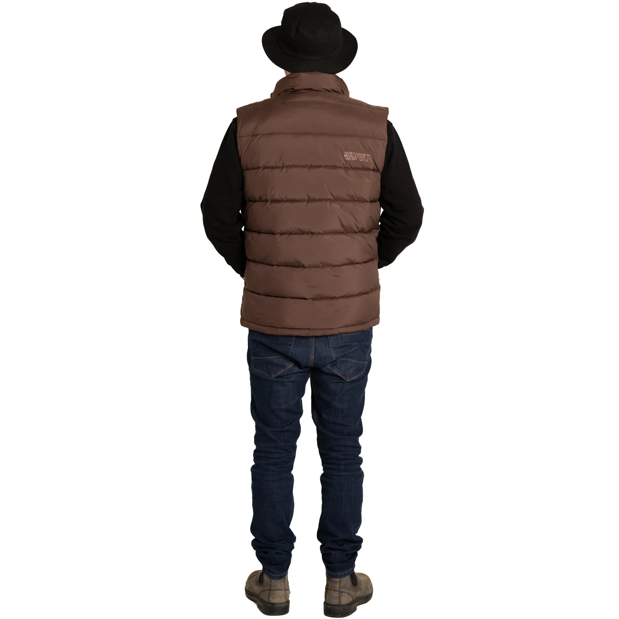 Man in brown puffer vest, black hat, jeans, and boots standing against white background
