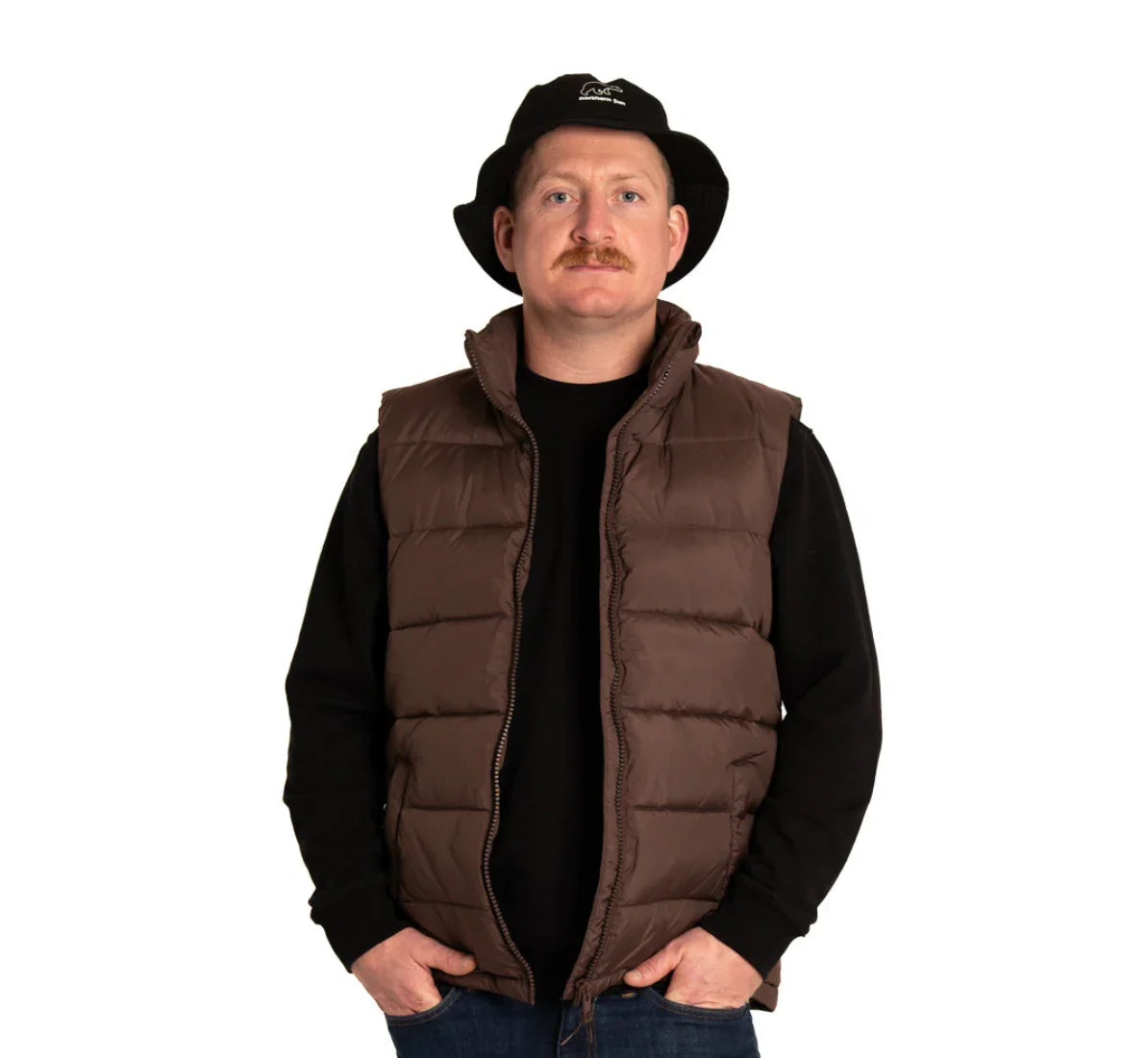 Man wearing brown puffer vest, black sweatshirt, and black bucket hat on white background