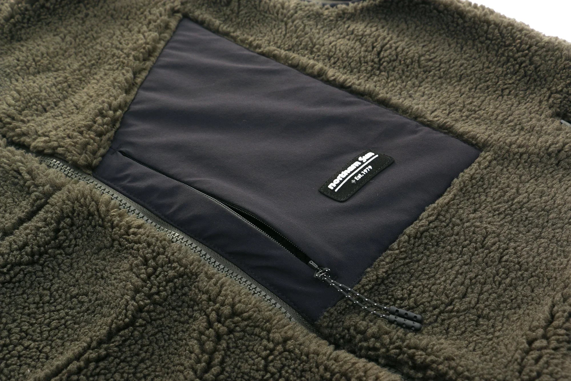 Green sherpa vest with black zipper pocket and Northern Sun logo patch detail