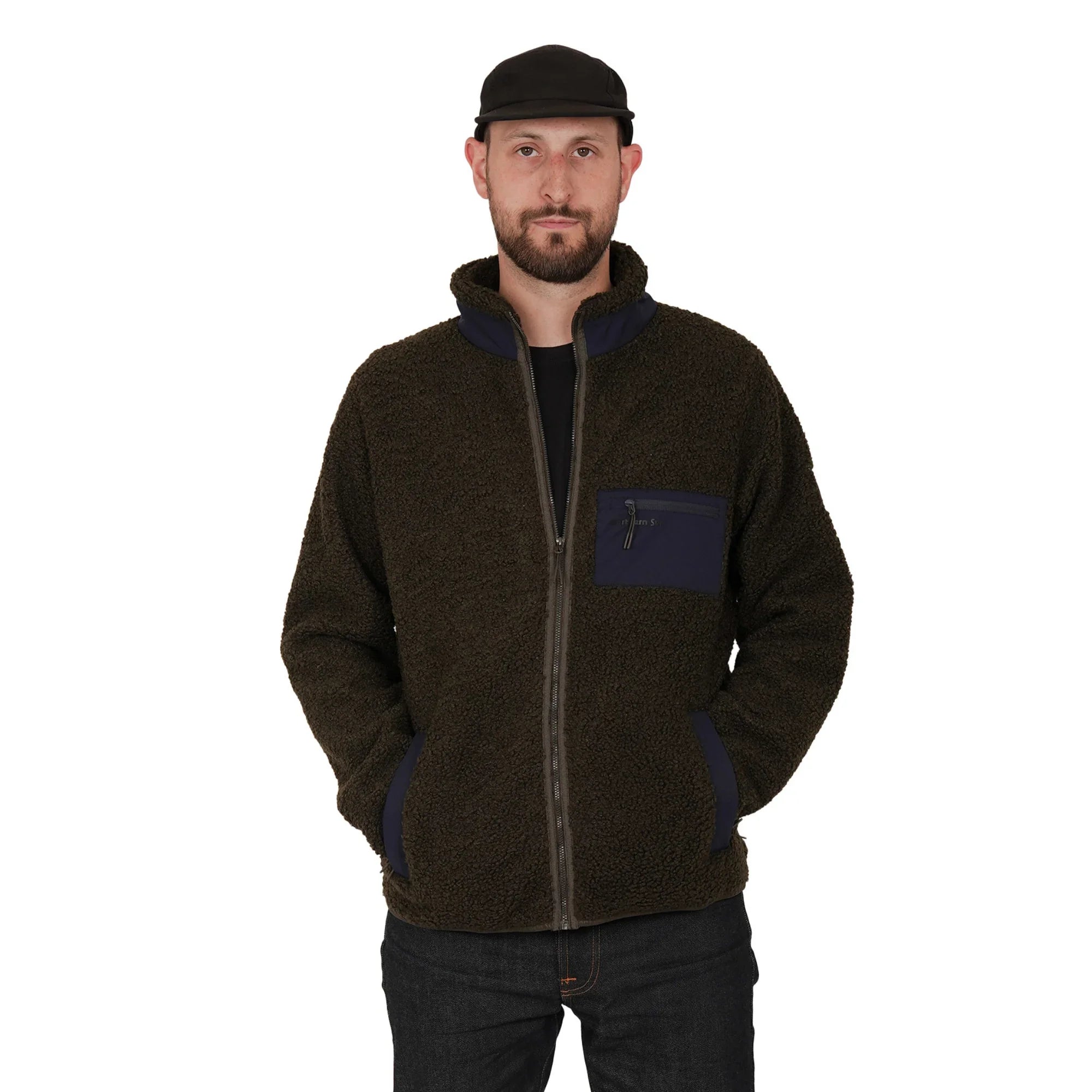 Man in brown teddy fleece jacket with navy details, black cap, standing against white background