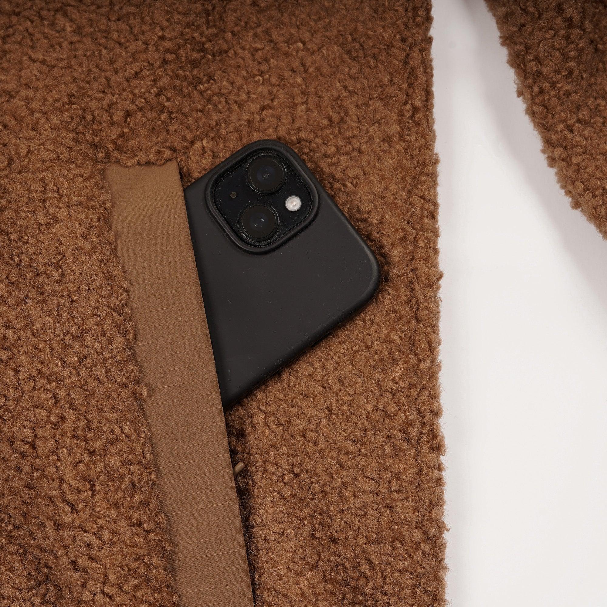 Brown teddy fleece men's jacket with phone in zip pocket, close-up view