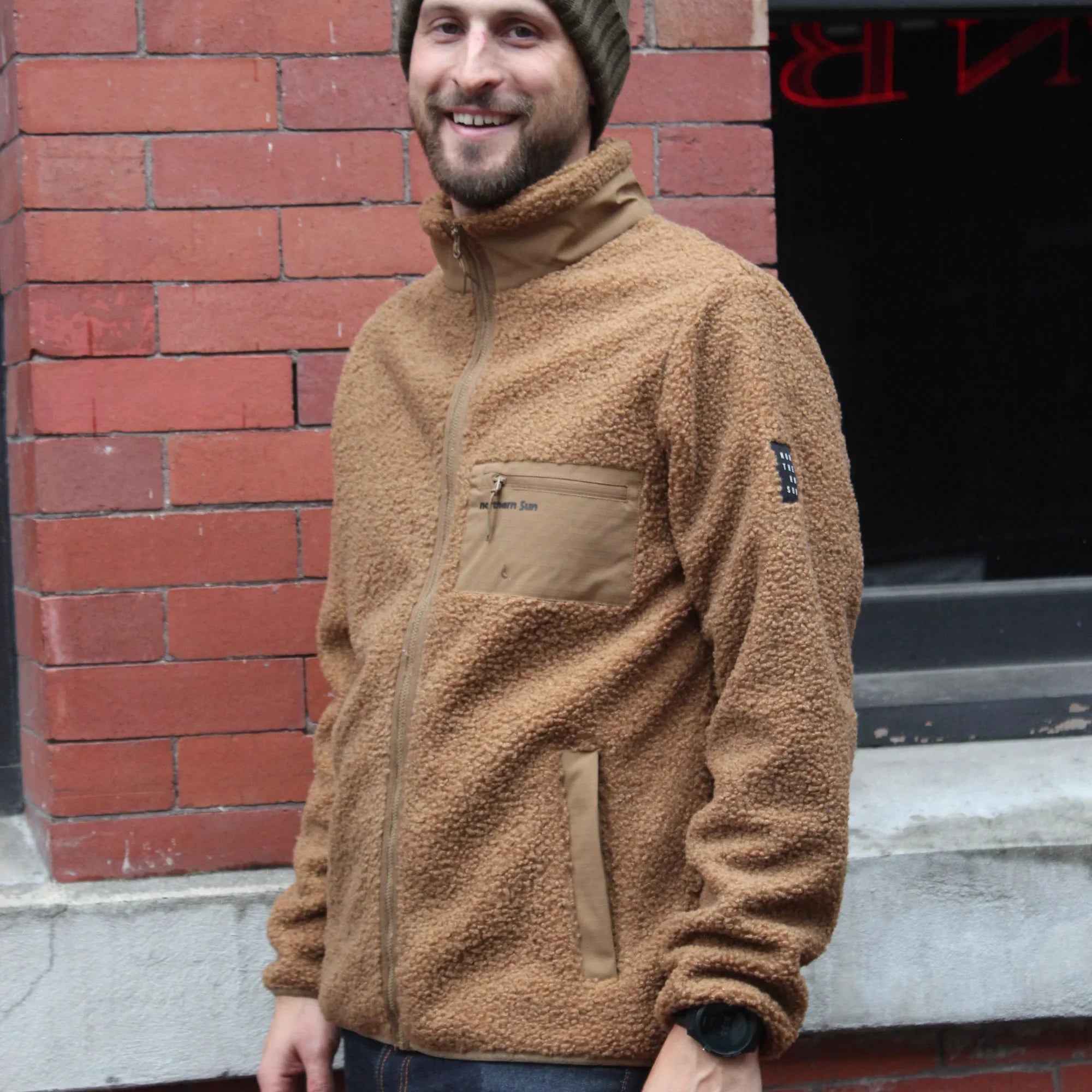 Man wearing tan teddy fleece jacket and green beanie in urban Vancouver setting