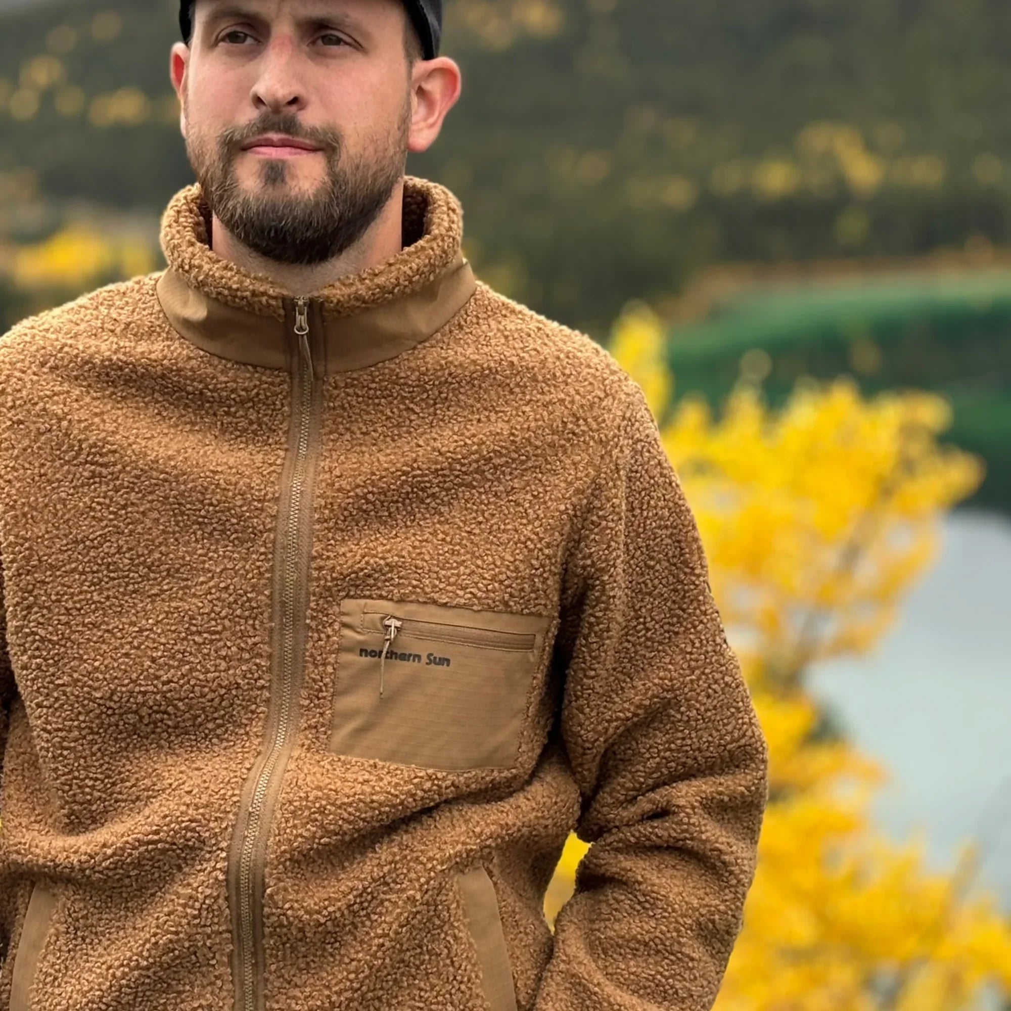 Man wearing Northern Sun brown teddy fleece jacket outdoors in Canadian fall landscape