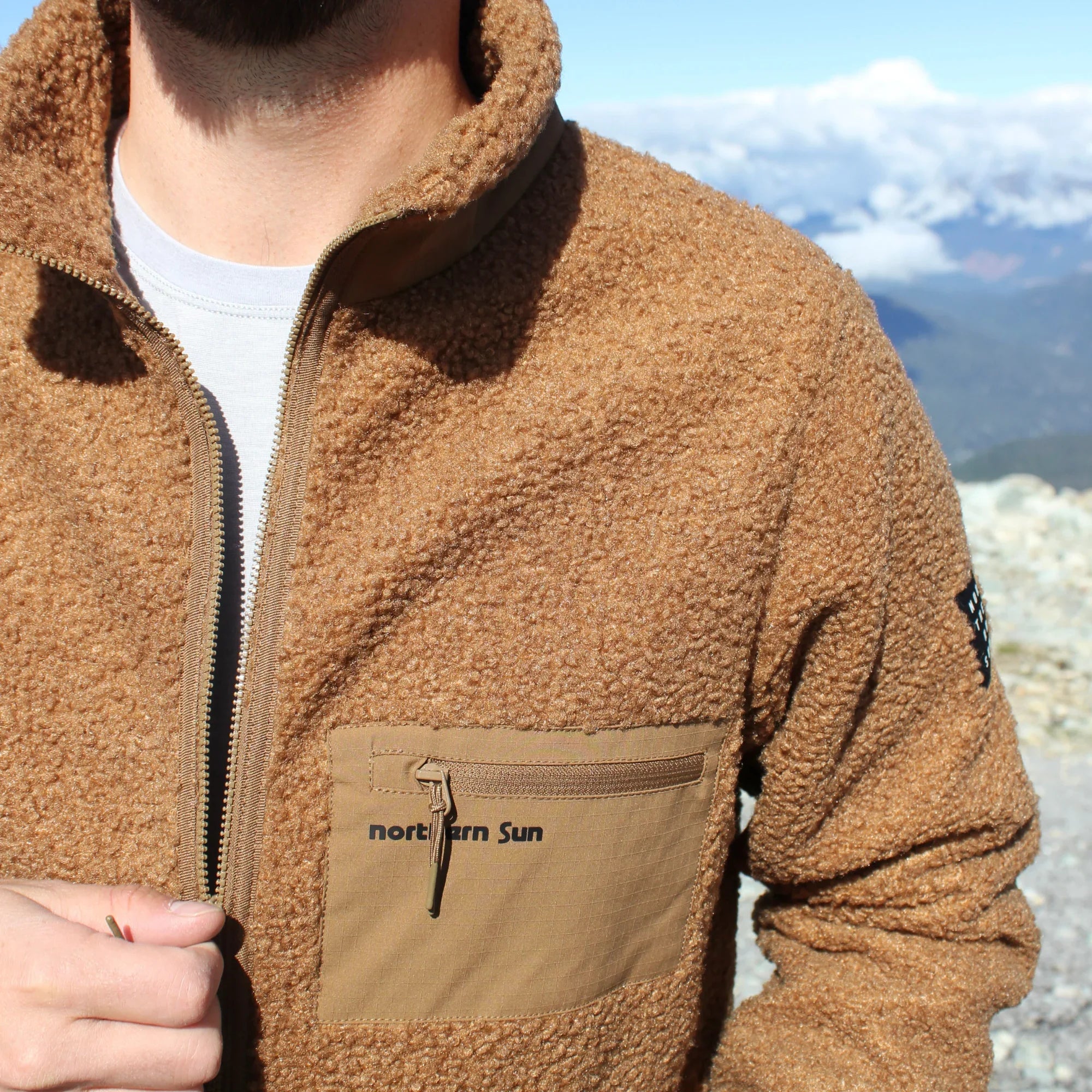 Man wearing brown Northern Sun teddy fleece jacket outdoors on a mountain