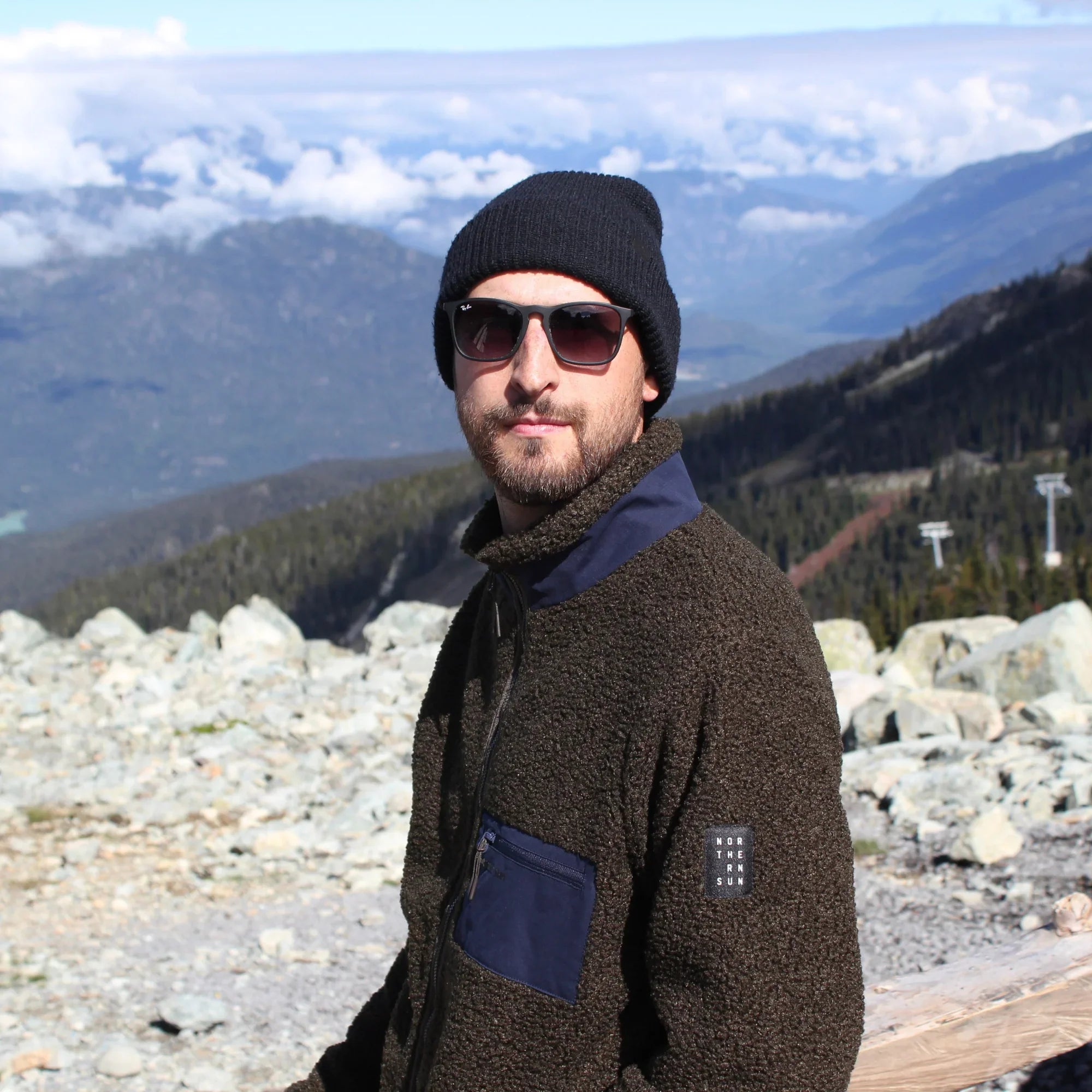 Man in teddy fleece jacket and beanie outdoors in BC mountains, rocky landscape, sunny day