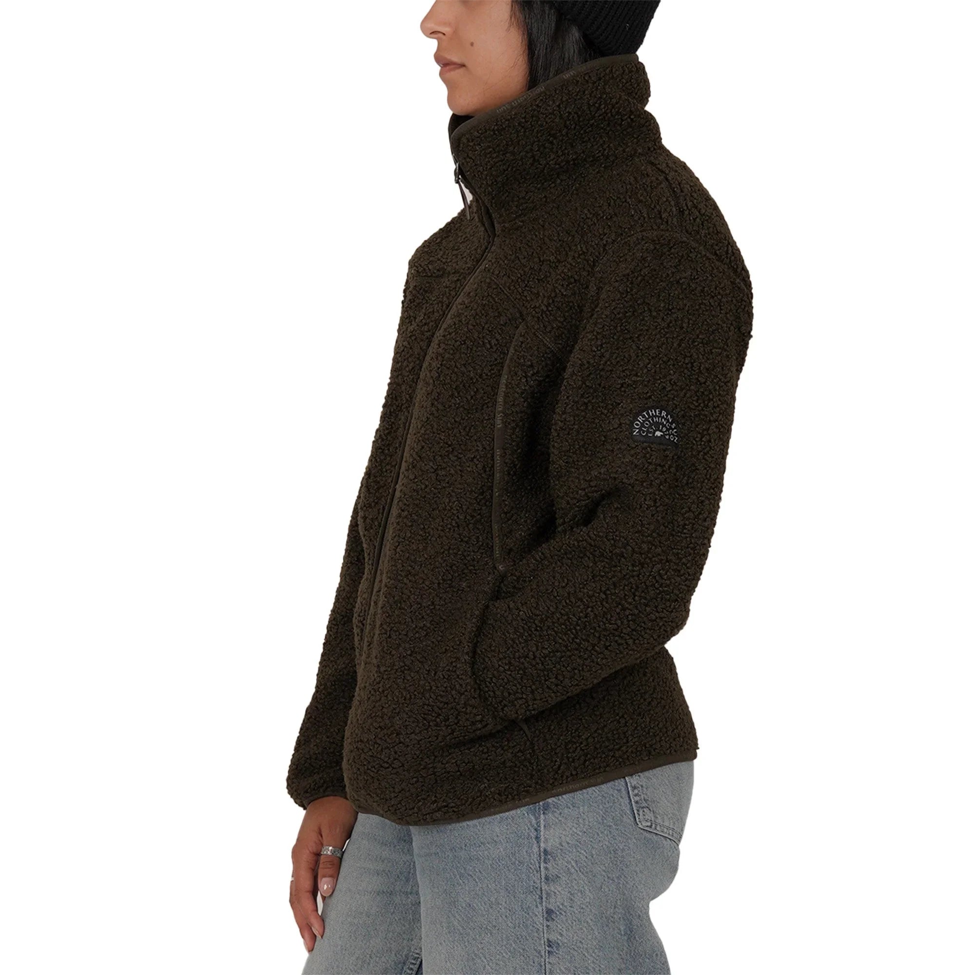 Woman in green teddy fleece jacket and jeans, side view, white background