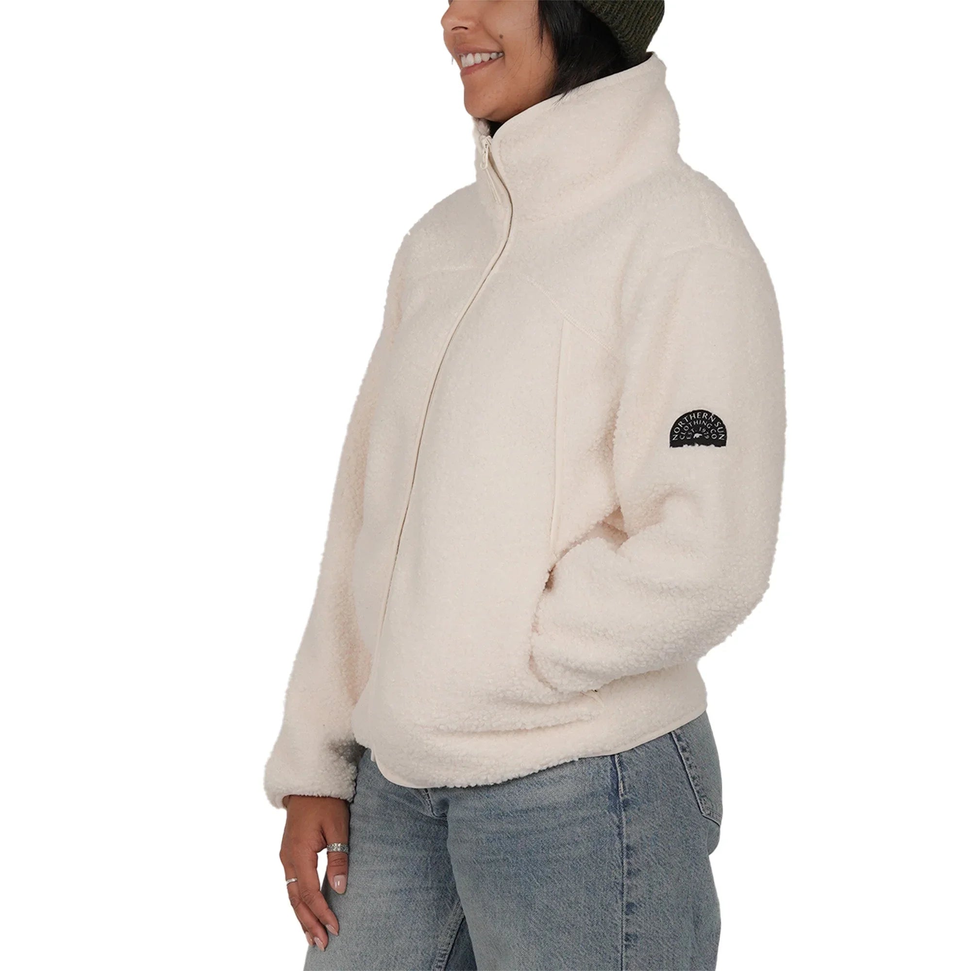 Woman wearing cream teddy fleece jacket and green beanie, side view, Northern Sun logo