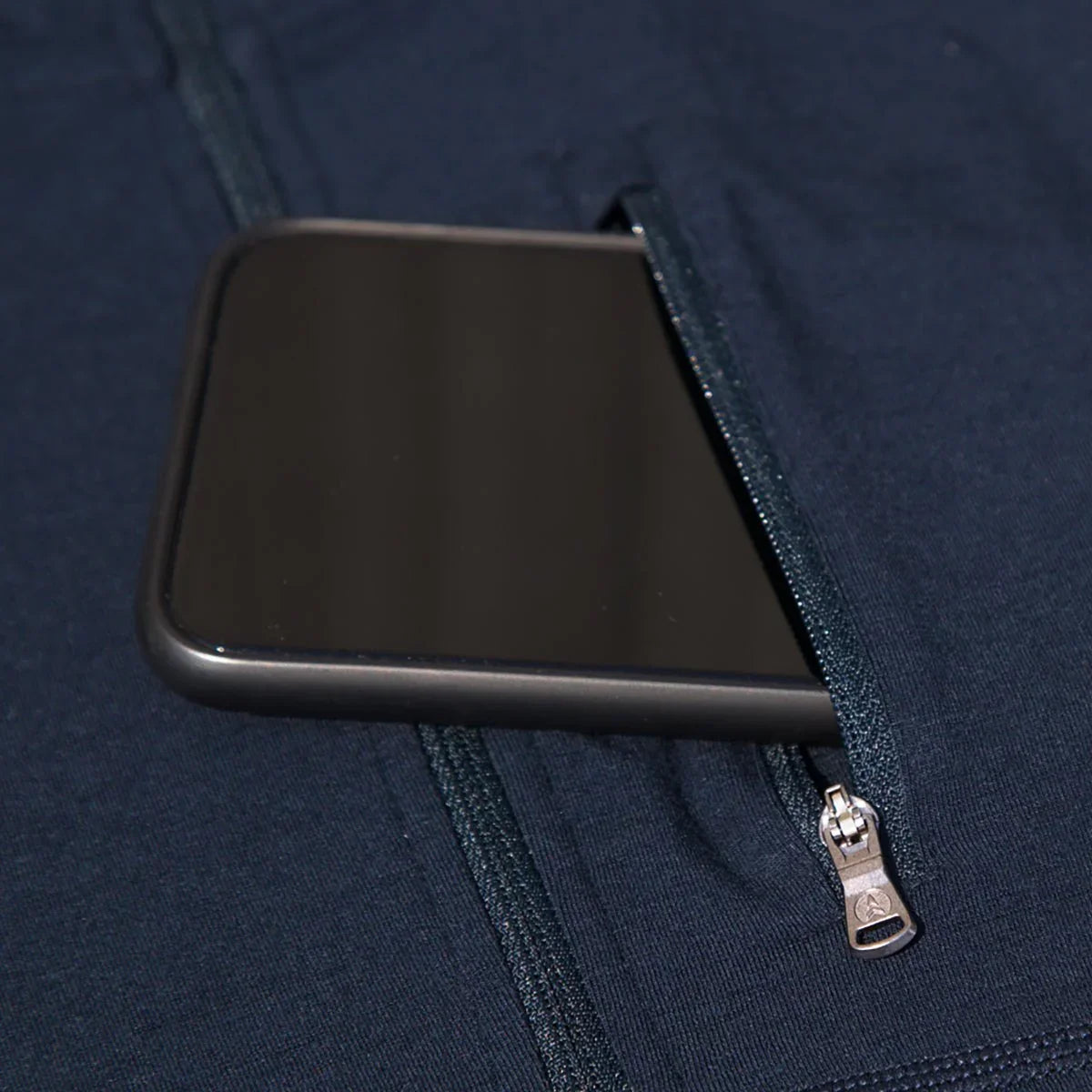 Closeup of a black phone in navy merino wool hoodie zip pocket