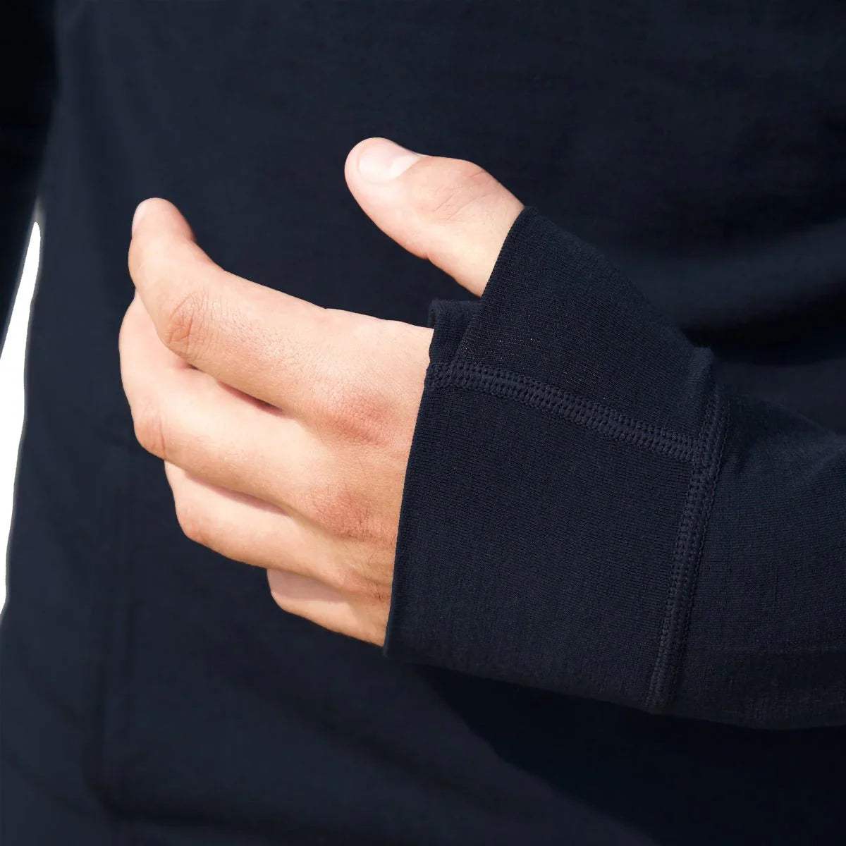 Close-up of a hand in a black merino wool hoodie sleeve with thumbhole detail