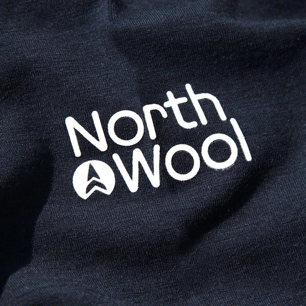 NorthWool logo in white on dark merino wool fabric, close-up texture detail