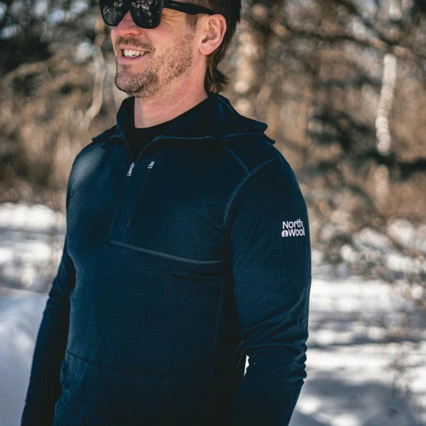 Man in NorthWool men's pullover outdoors in winter wearing sunglasses, forest background