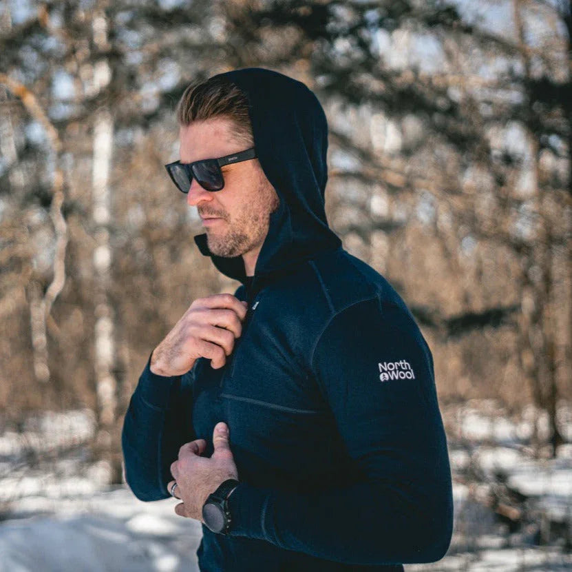 Man wearing North Wool men's hoodie outdoors in snowy winter forest, lifestyle apparel