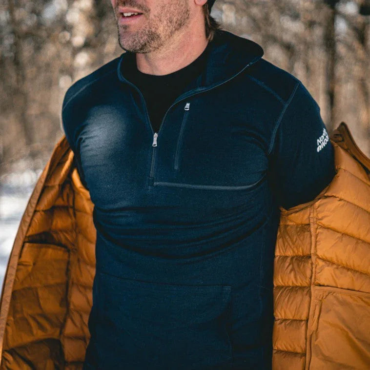 Man outdoors putting on orange insulated jacket over blue North Wool shirt in winter