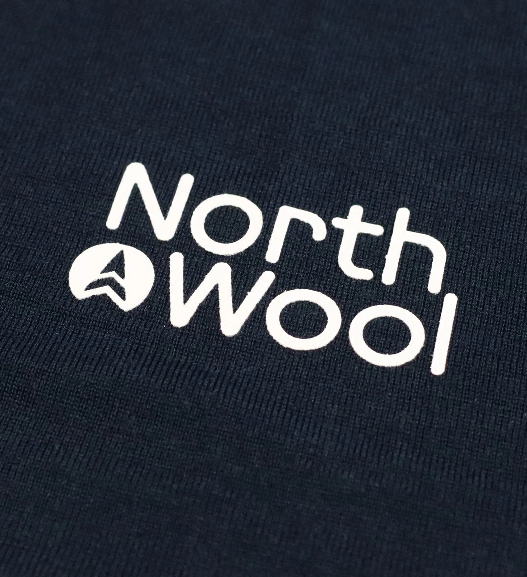 North Wool logo on navy blue merino wool sweater fabric close-up